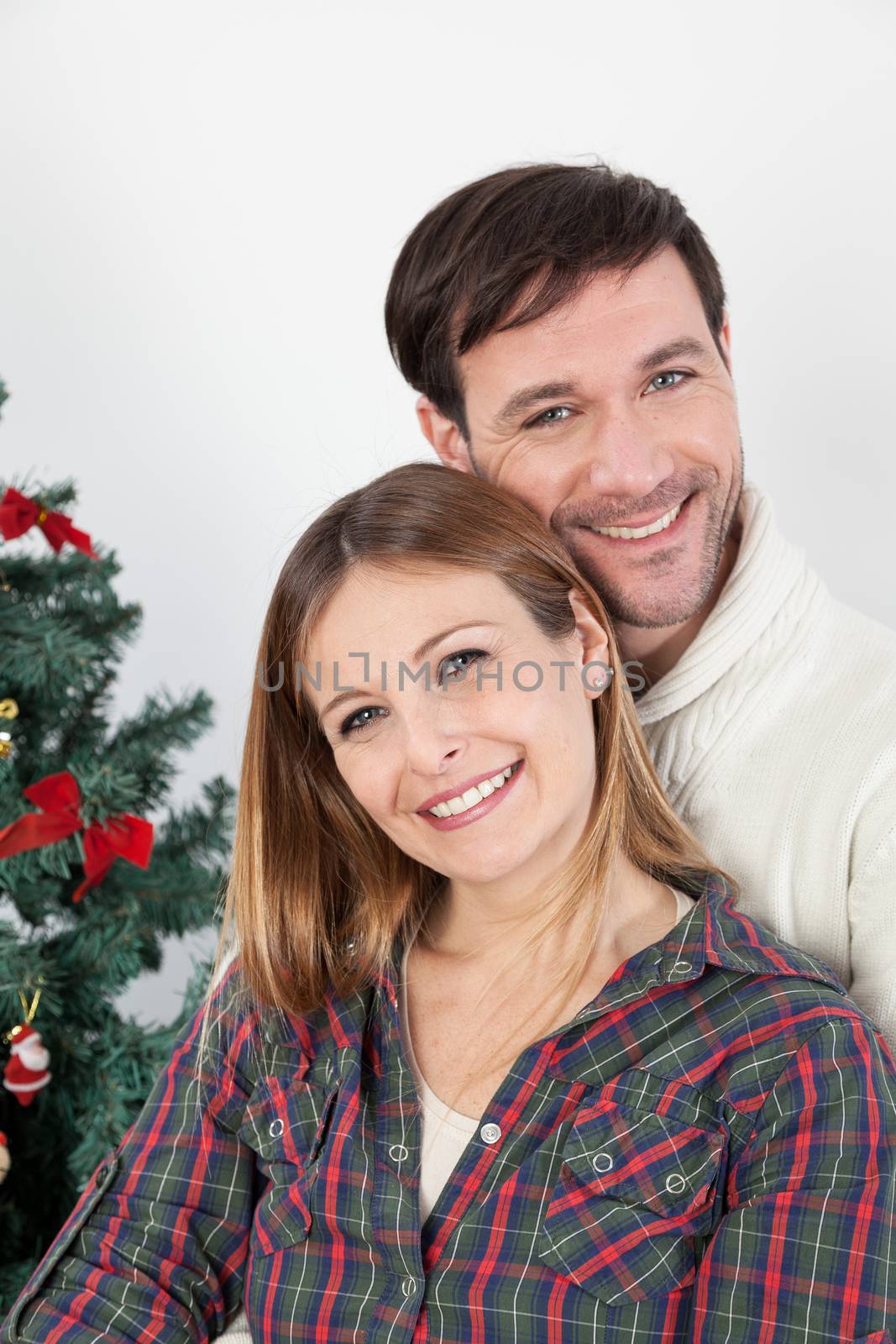 Couple smiling beside the chrismas tree by ifilms
