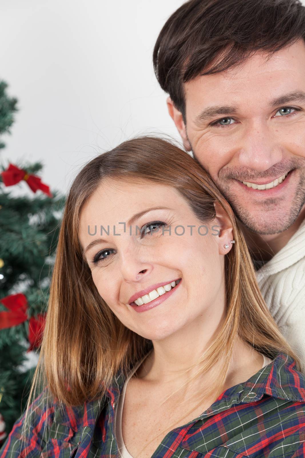 Couple smiling beside the chrismas tree by ifilms