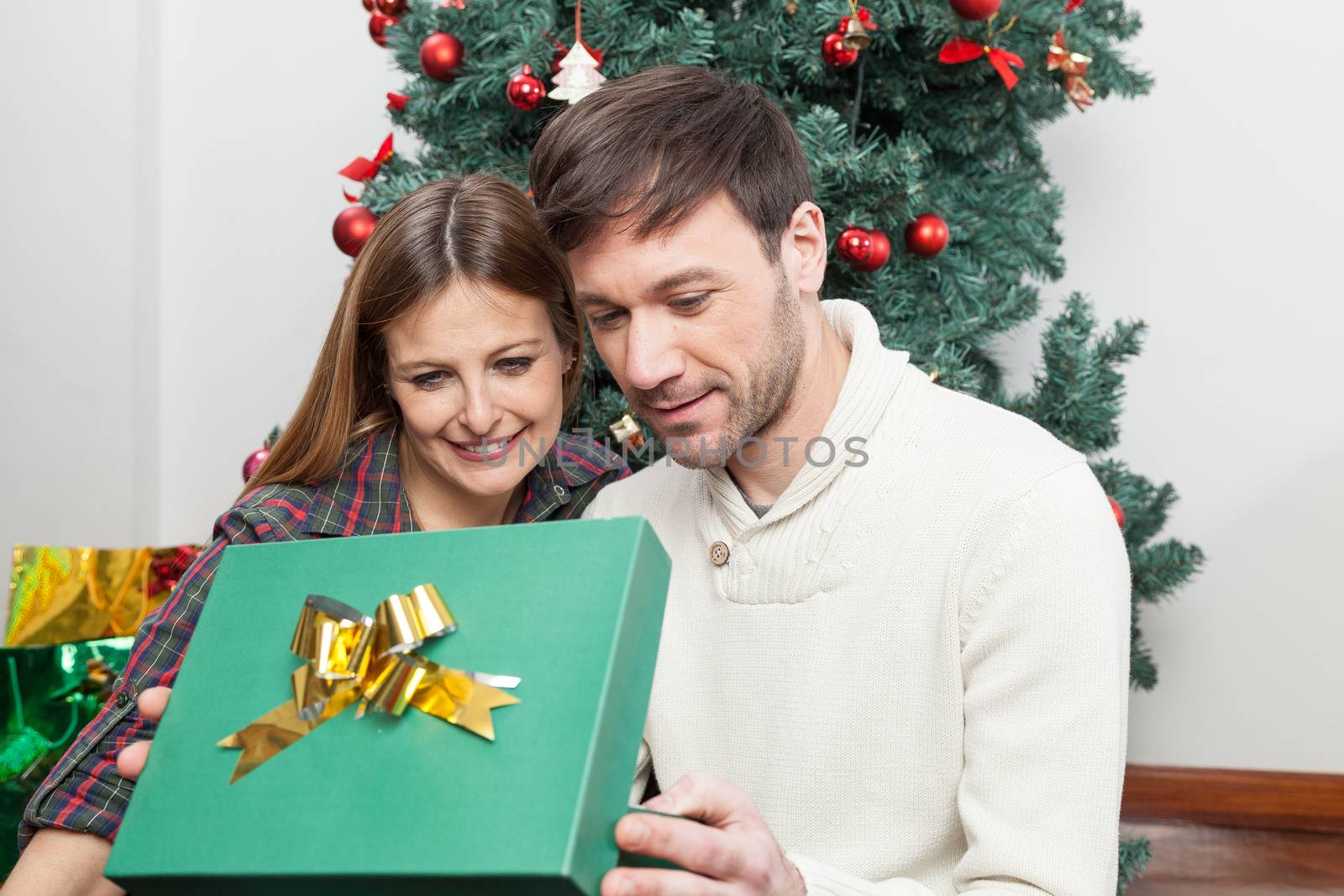 Beauty couple opening a christmas gift by ifilms