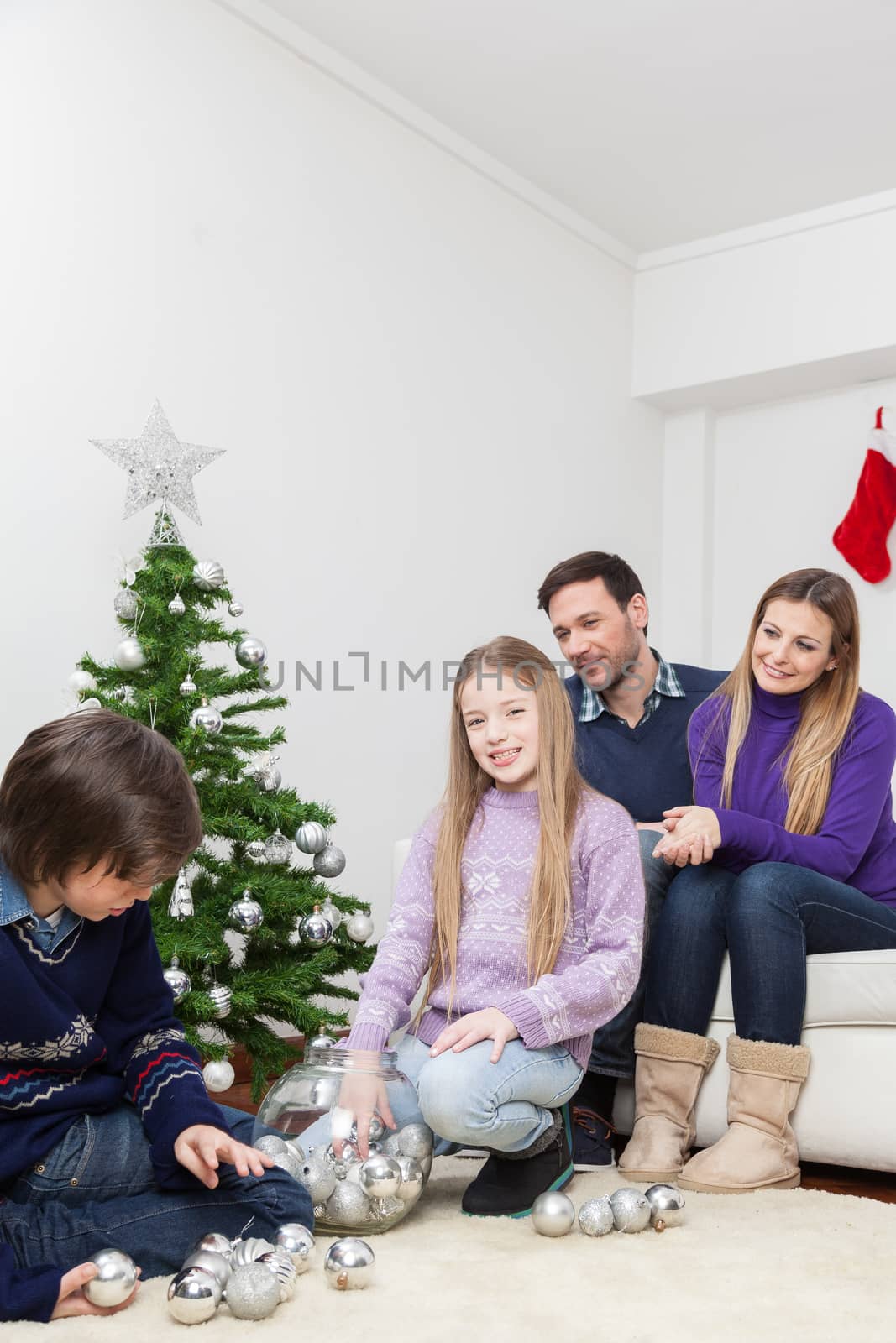 Happy family preparing the christmas tree by ifilms