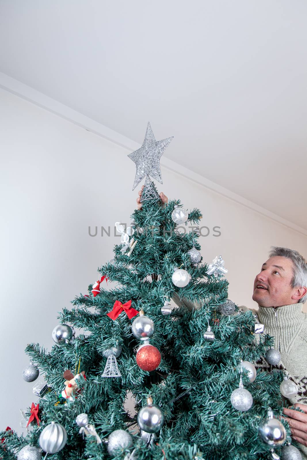 35-40, beautiful, caucasian, celebration, christmas, decorate, decorated, decoration, festive, gift, gifts, green, hand, holiday, model, new, old, ornament, pine, present, presents, property, red, releases, ribbon, santa, placing, shiny, silver, star, tree, vertical, white, winter, xmas, year, years, putting, decorating, tall, man, men, balls