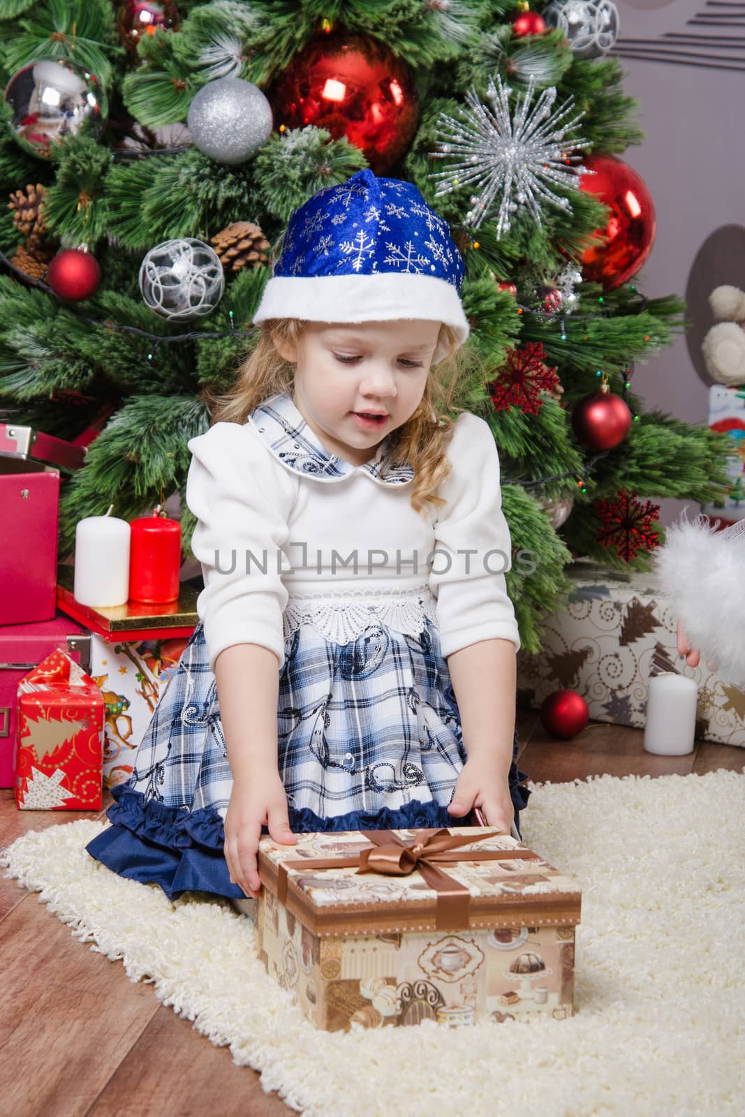 Girl sitting on a rug in a Christmas tree with gifts