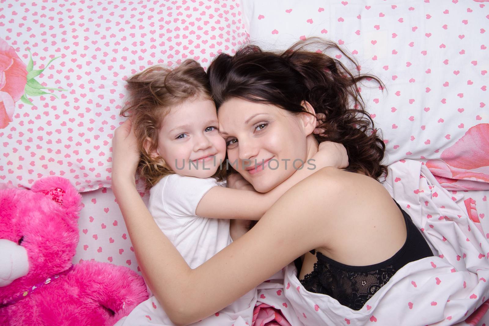 Mom and daughter with an excellent mood lie in bed