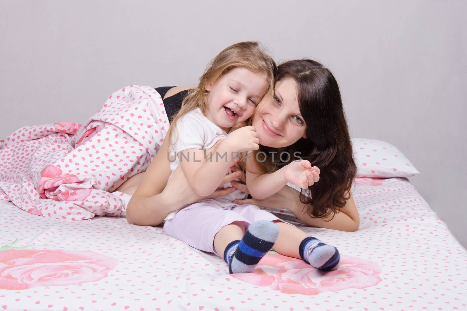 Mom and daughter with an excellent mood sitting on the bed