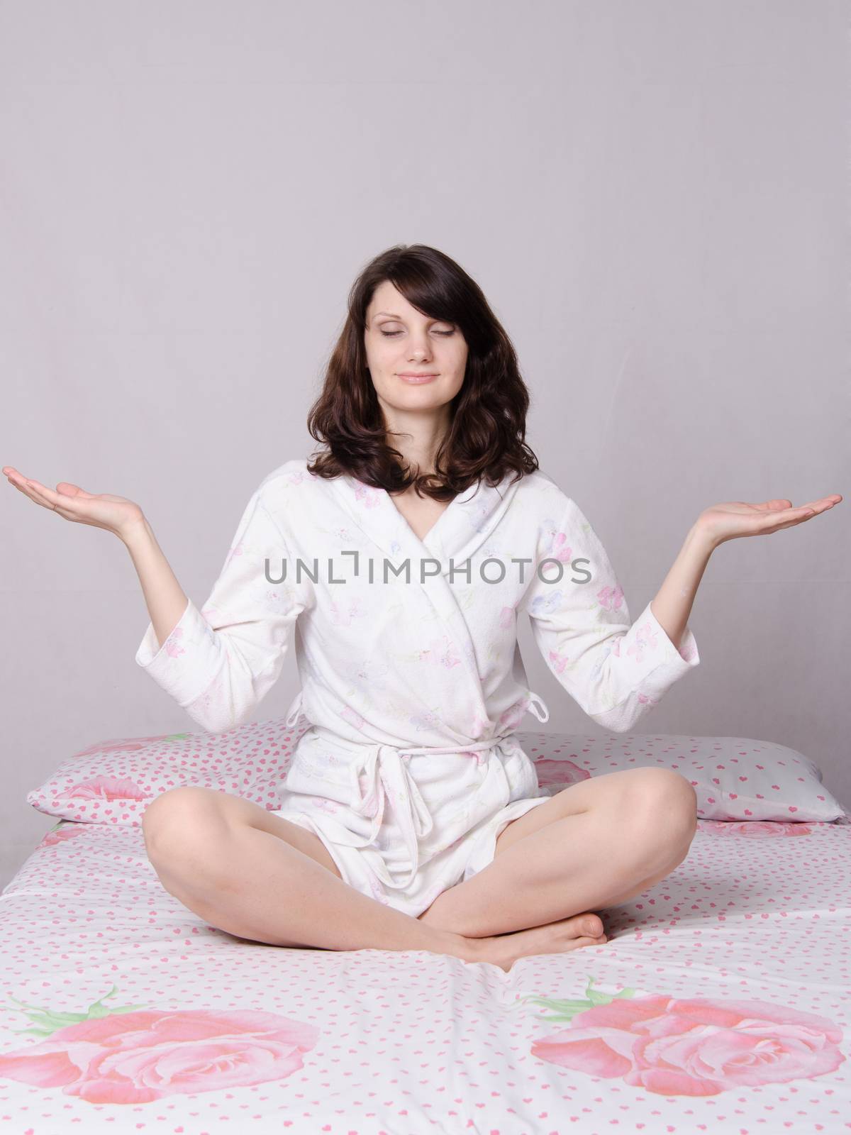Young beautiful woman waking up in the morning meditating sitting in bed