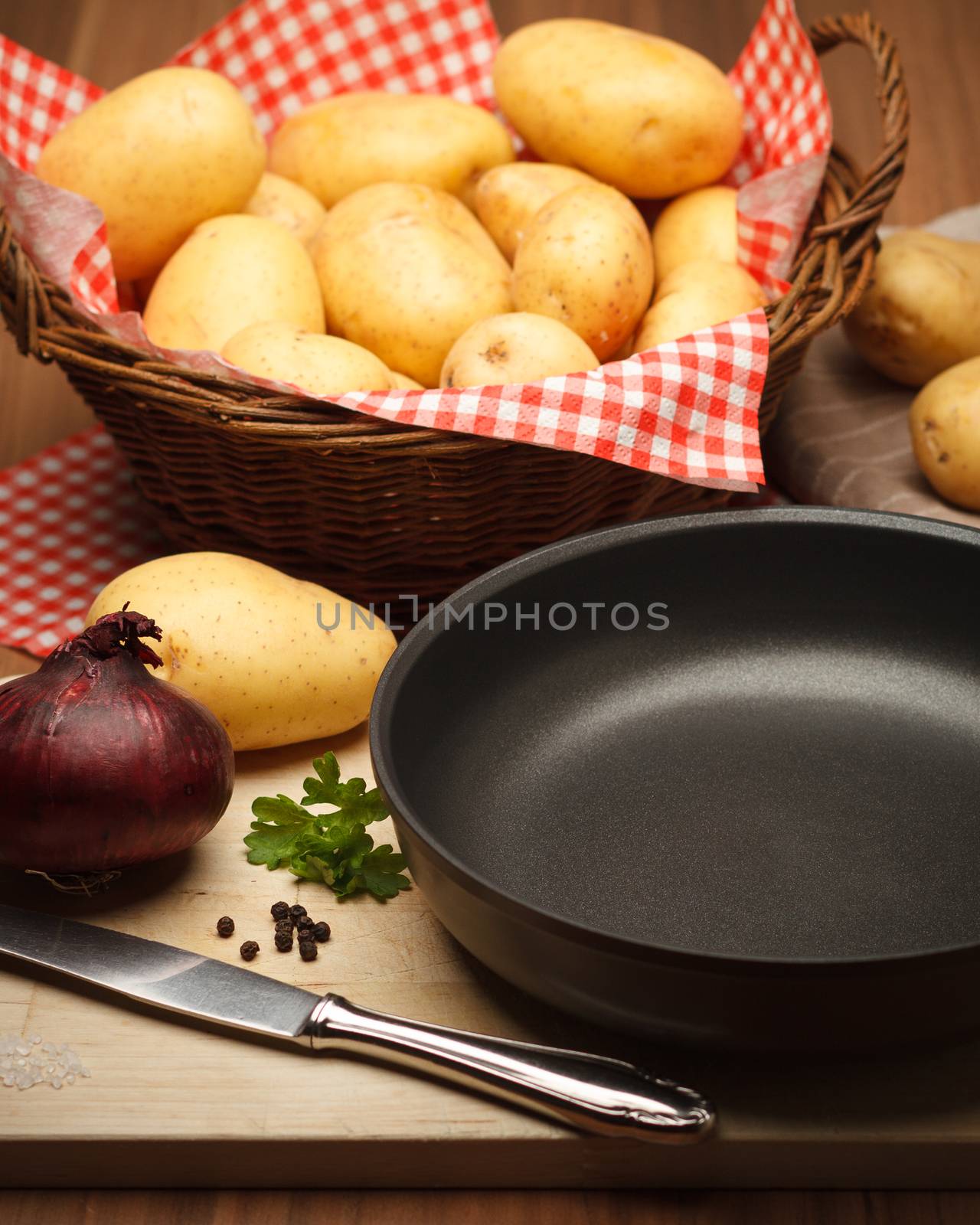 Fryingpan with potatoes an onion on wood