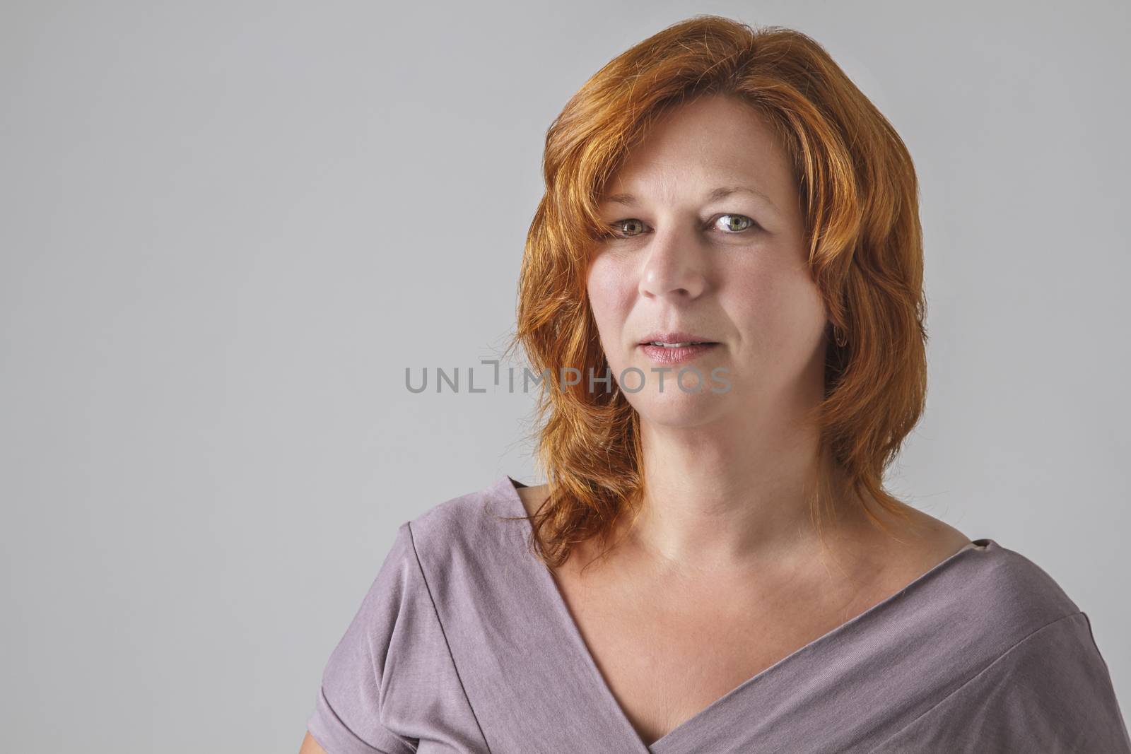beautiful woman in her forties with red hair, wearing a grey shirt