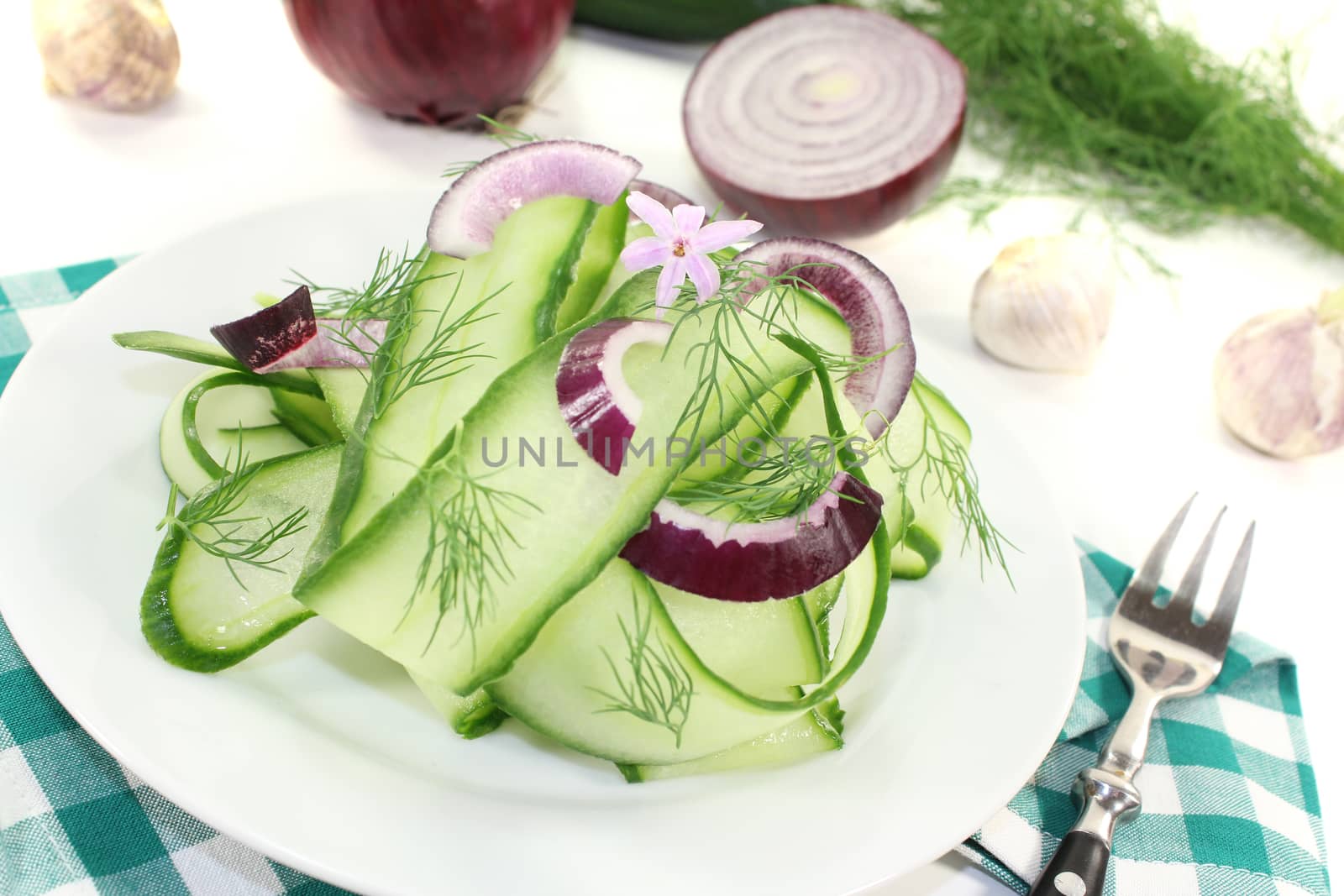 Cucumber salad with red onions, garlic flower and dill on a plate