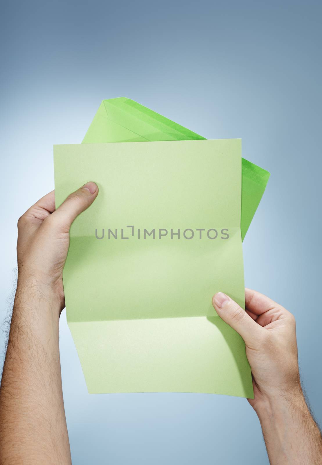 Man holding a green envelope and a blank green letter in his hands.