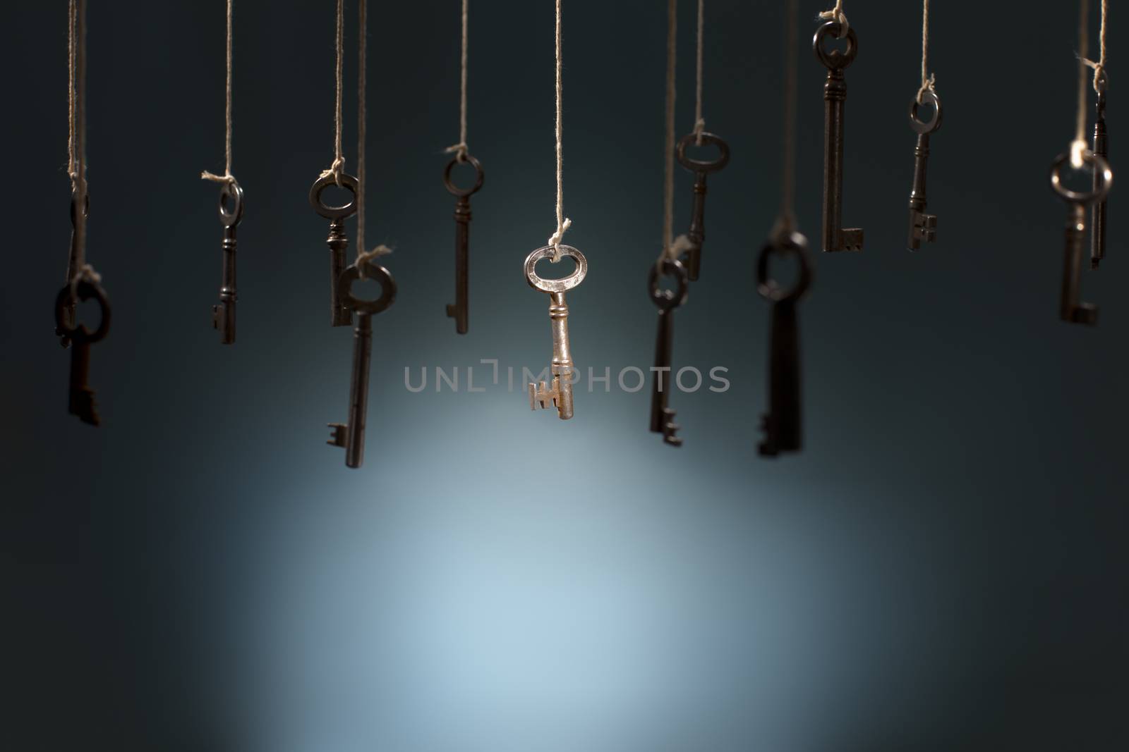 Old keys hanging on strings. One key in the middle is in spotlight focus.