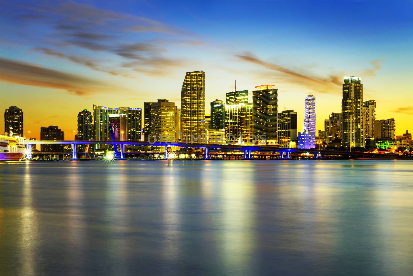 Miami city skyline panorama at dusk with urban skyscrapers over sea with reflection 