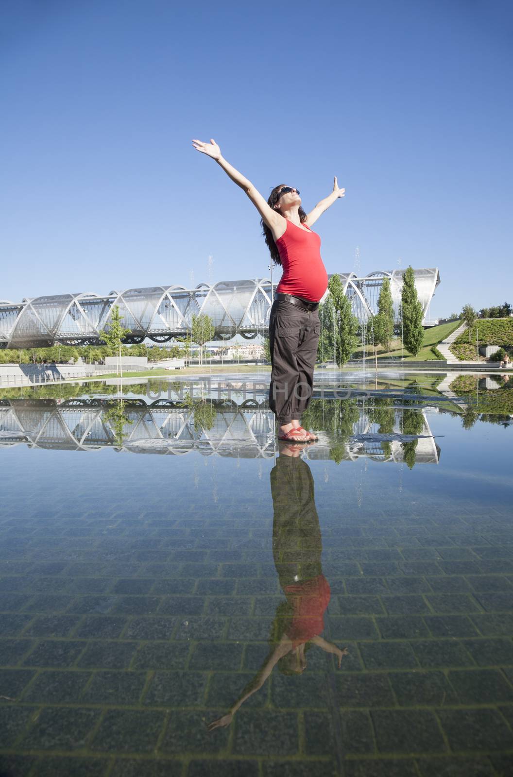 happy pregnant woman open arms on water surface in Madrid city