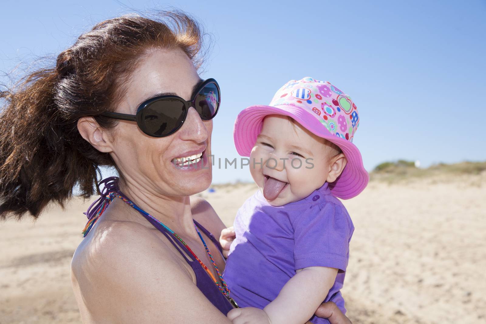 portrait of mother and baby hugging and laughing at beach