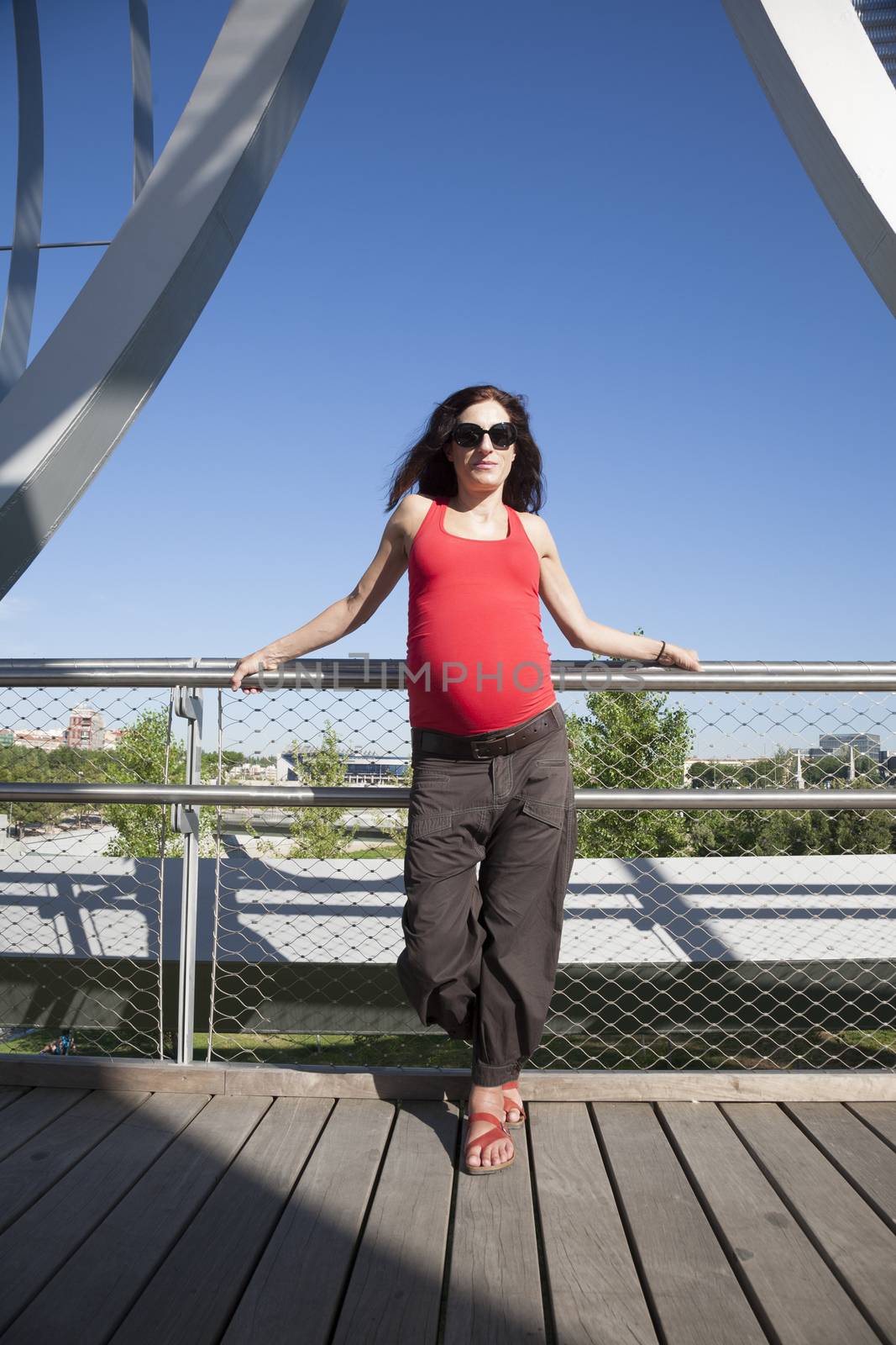 front pregnant woman leaning on railing blue sky background