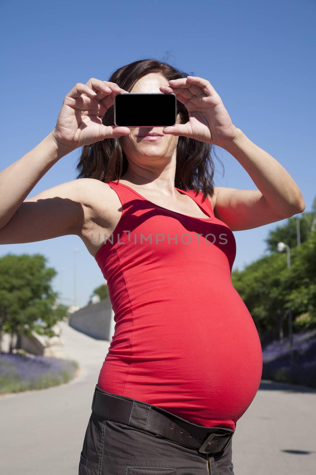smiling pregnant woman with smartphone in her hands