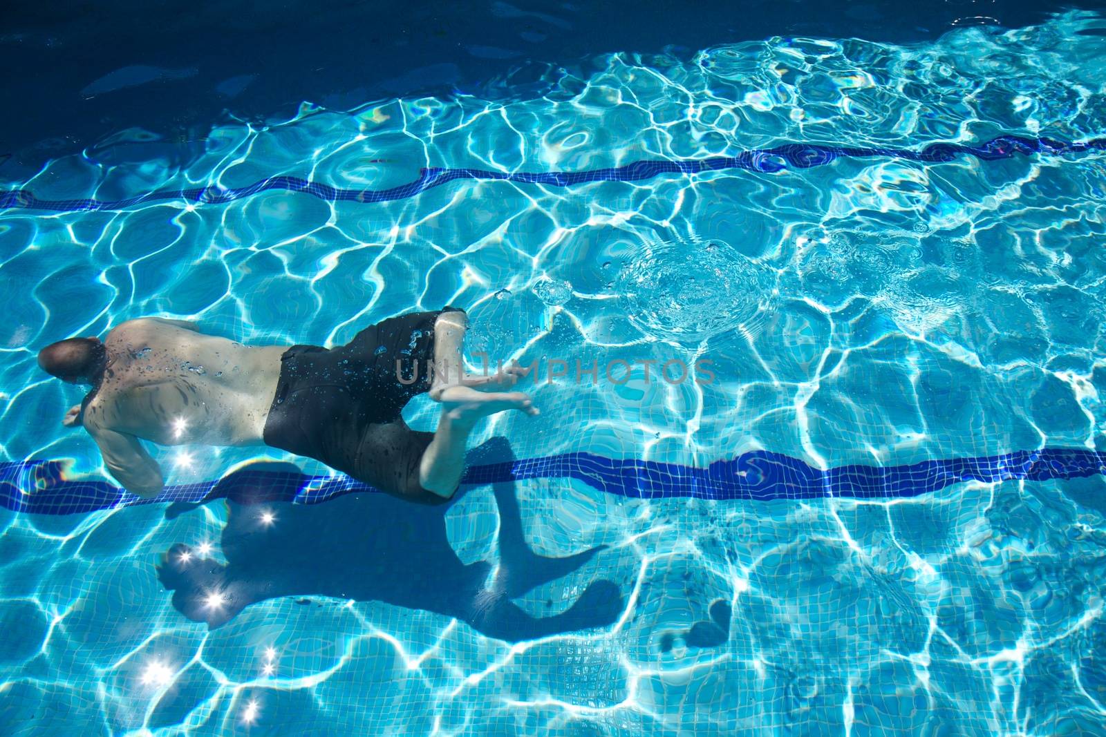 man with swimsuit swimming on a blue water pool