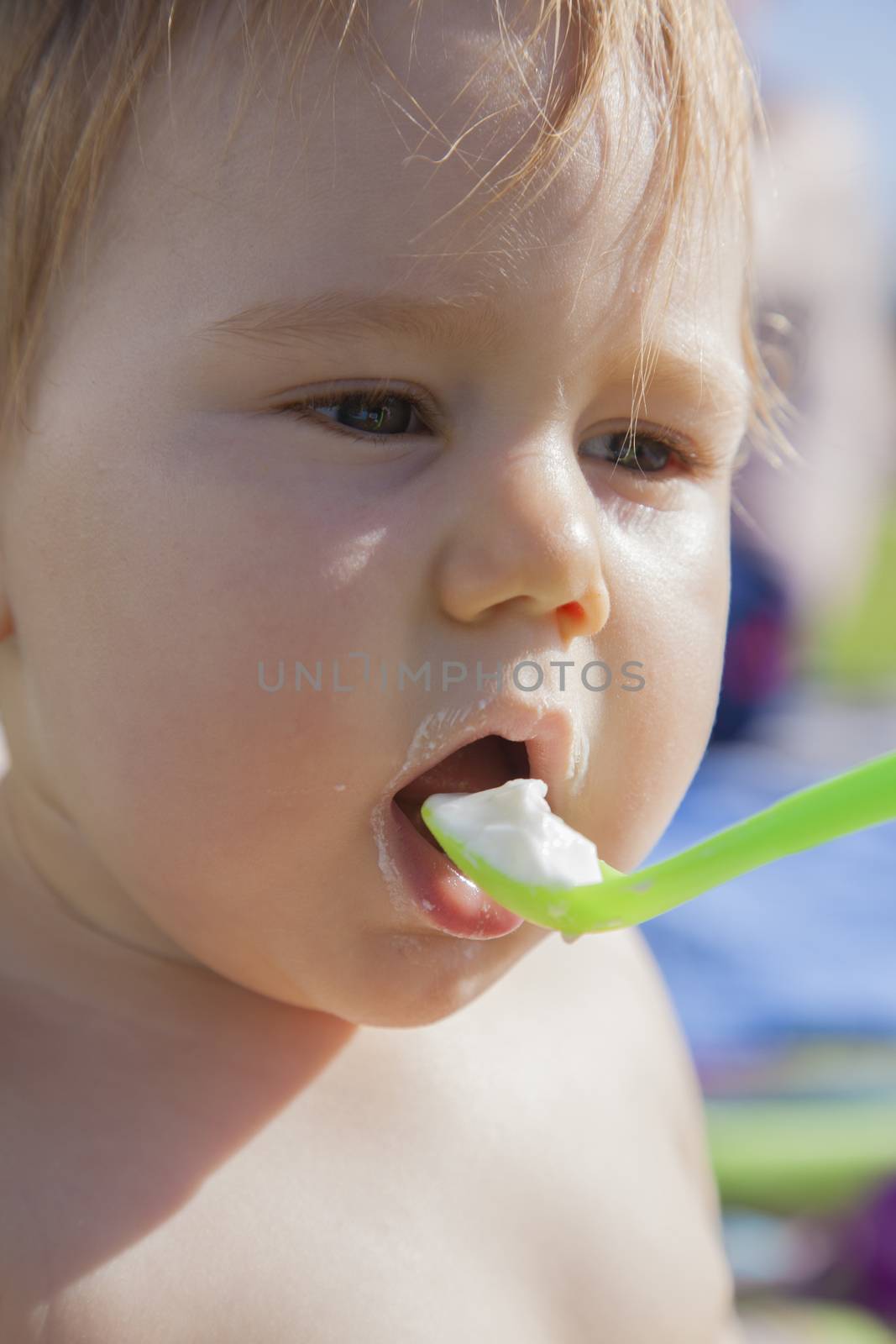 portrait of baby eating from green spoon