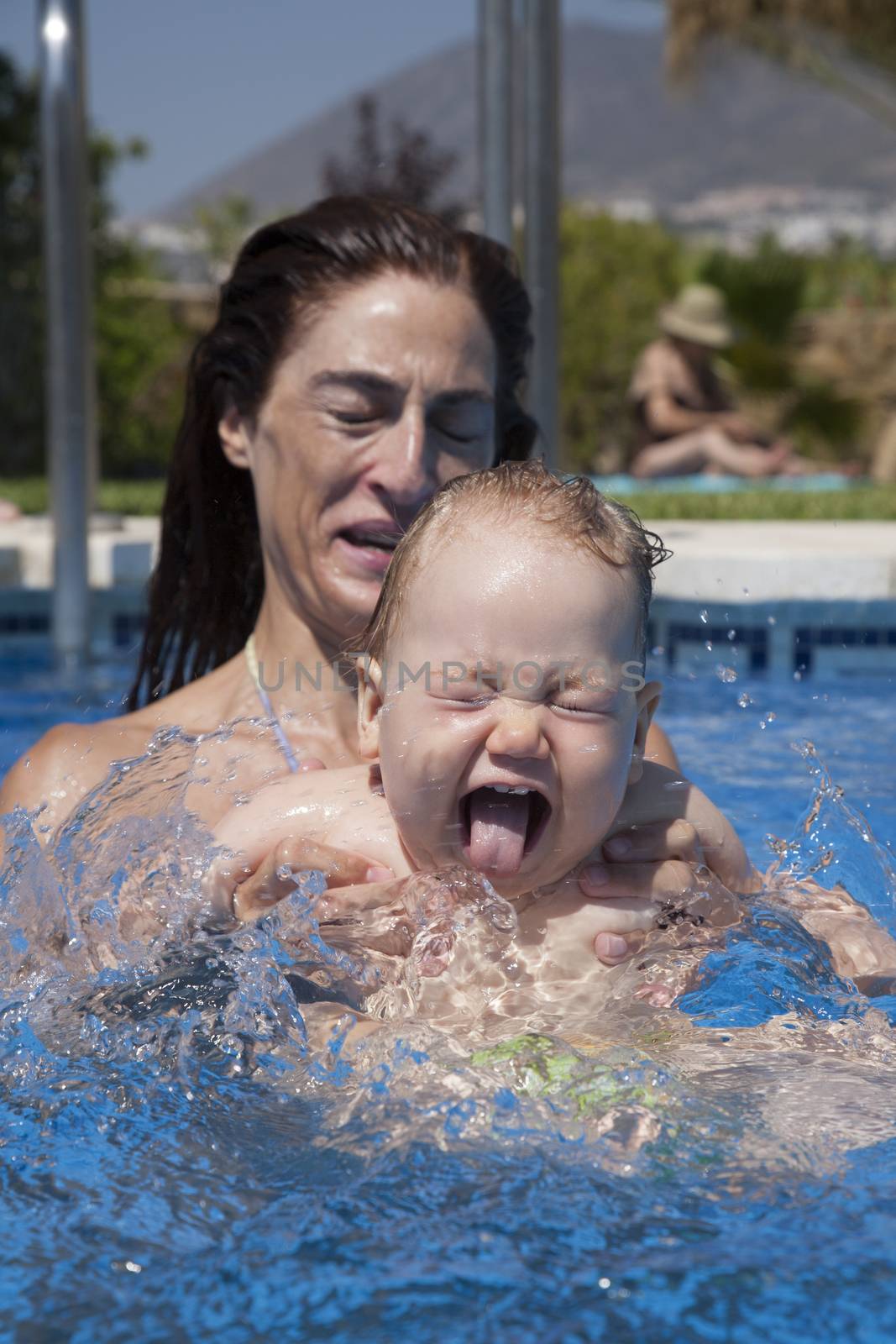 mother and baby in swimming pool splashing