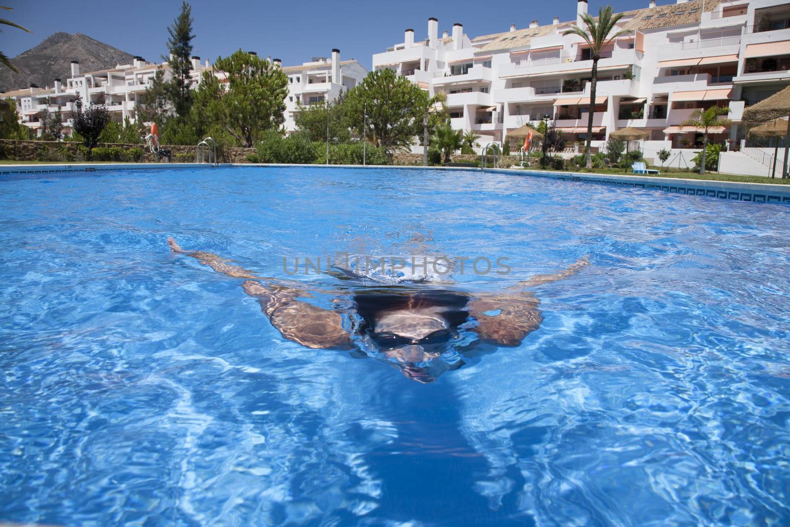 woman with goggles diving breaststroke in a blue pool