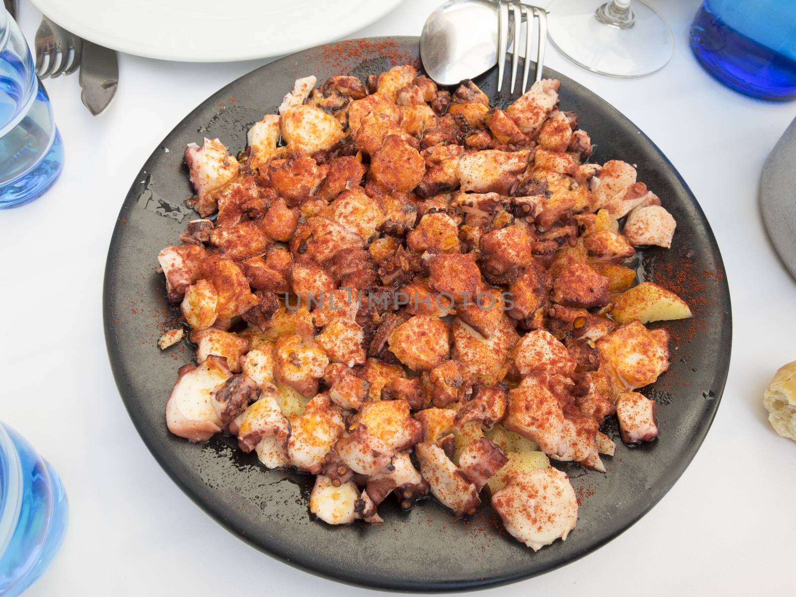 black dish with octopus and potatoes cooked like Galician style with paprika