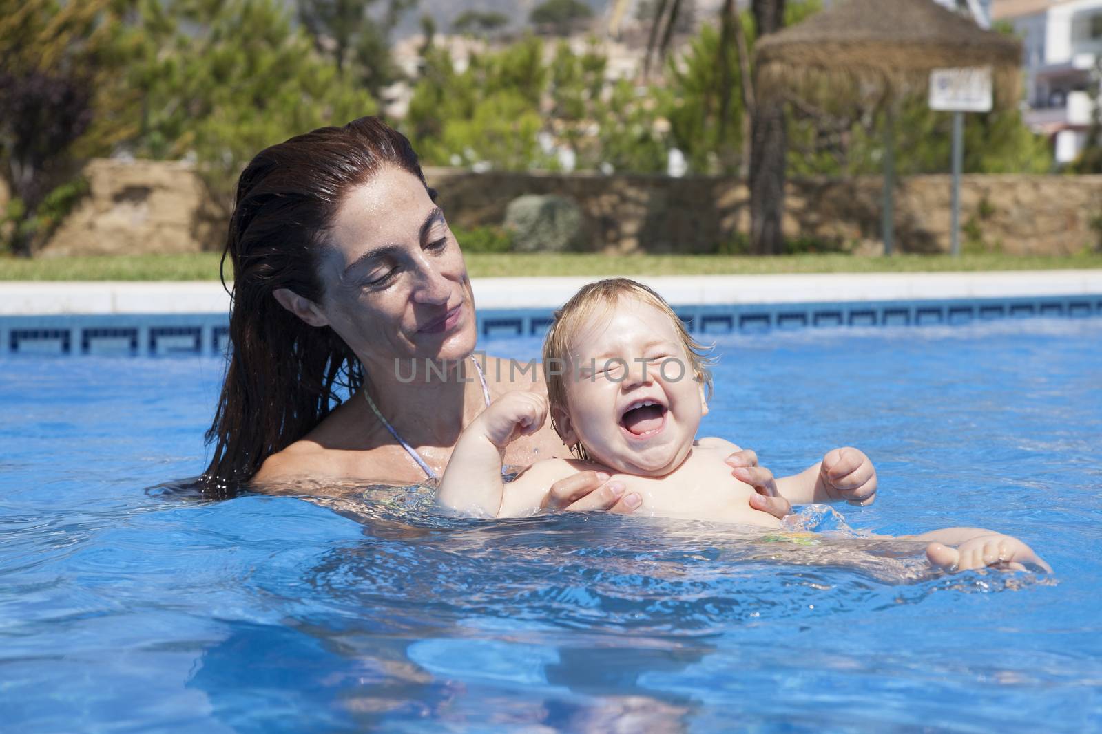 mother and baby in swimming pool laughing