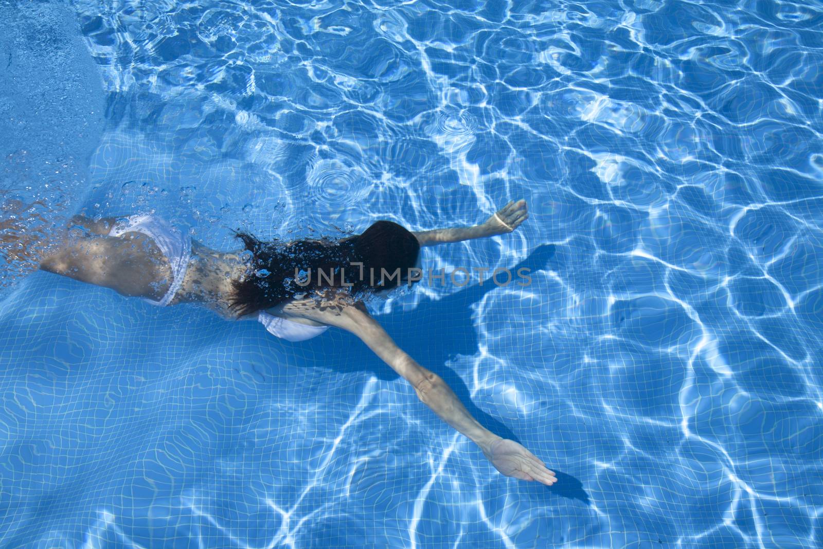 woman with white bikini swimming open arms in a blue pool