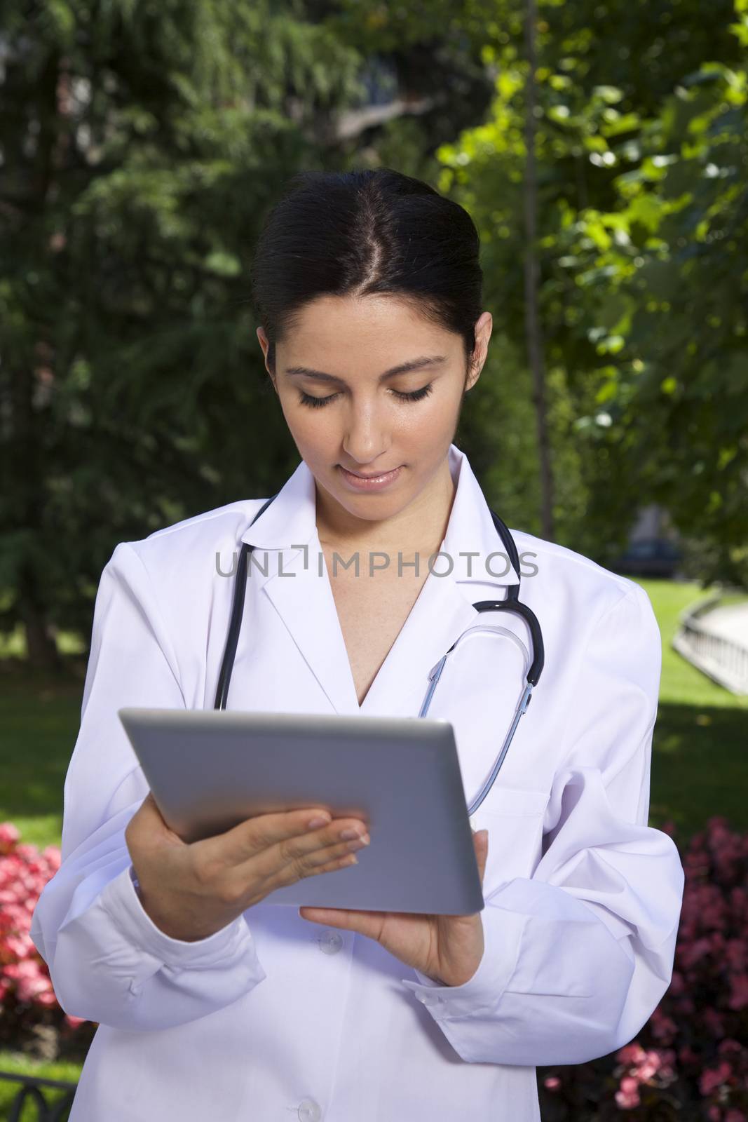 doctor young woman with tablet over a green trees background in Madrid city Spain

