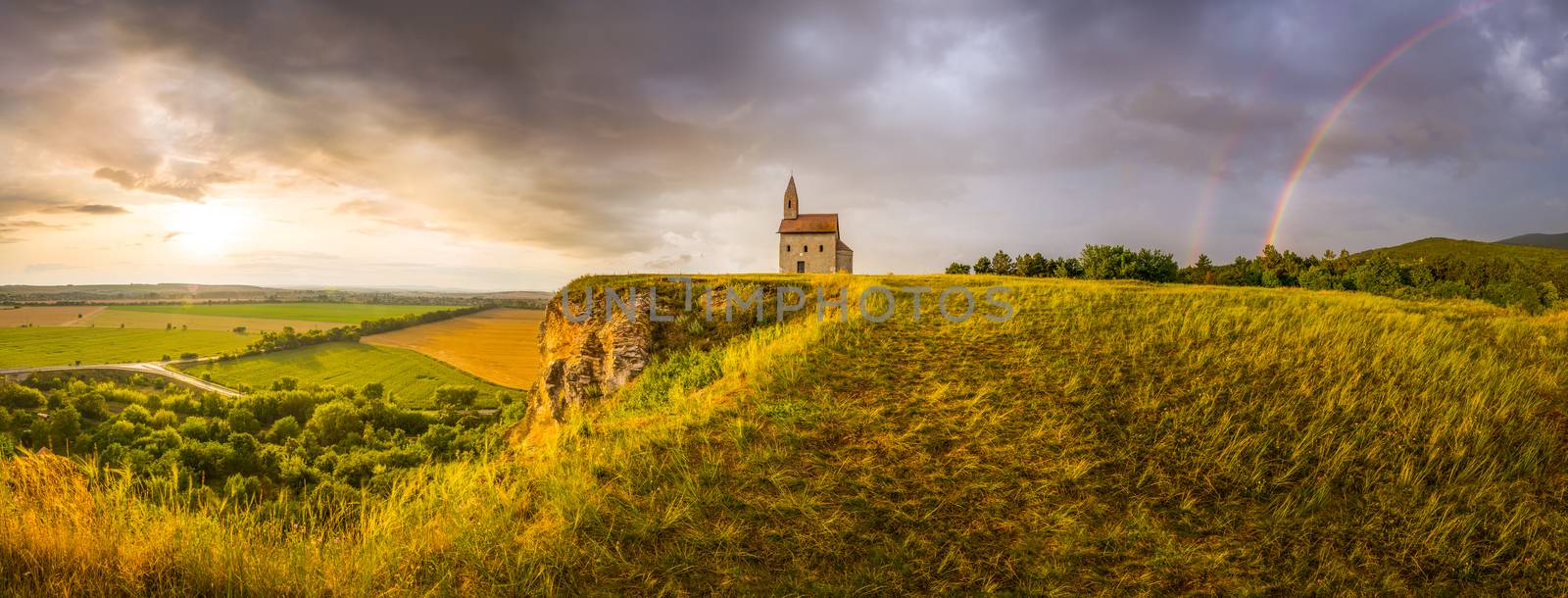 Old Roman Catholic Church of St. Michael the Archangel with Rainbow on the Hill at Sunset in Drazovce, Slovakia