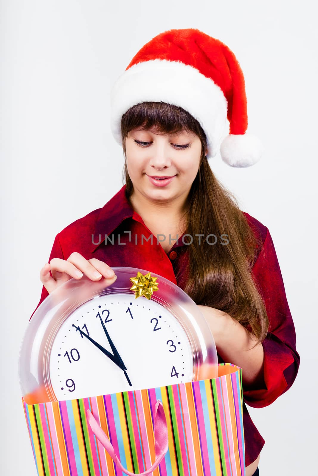 Young blue-eyed beautiful girl in santa hat with clock