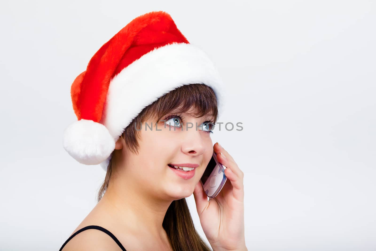 Young blue-eyed beautiful girl in santa hat with phone