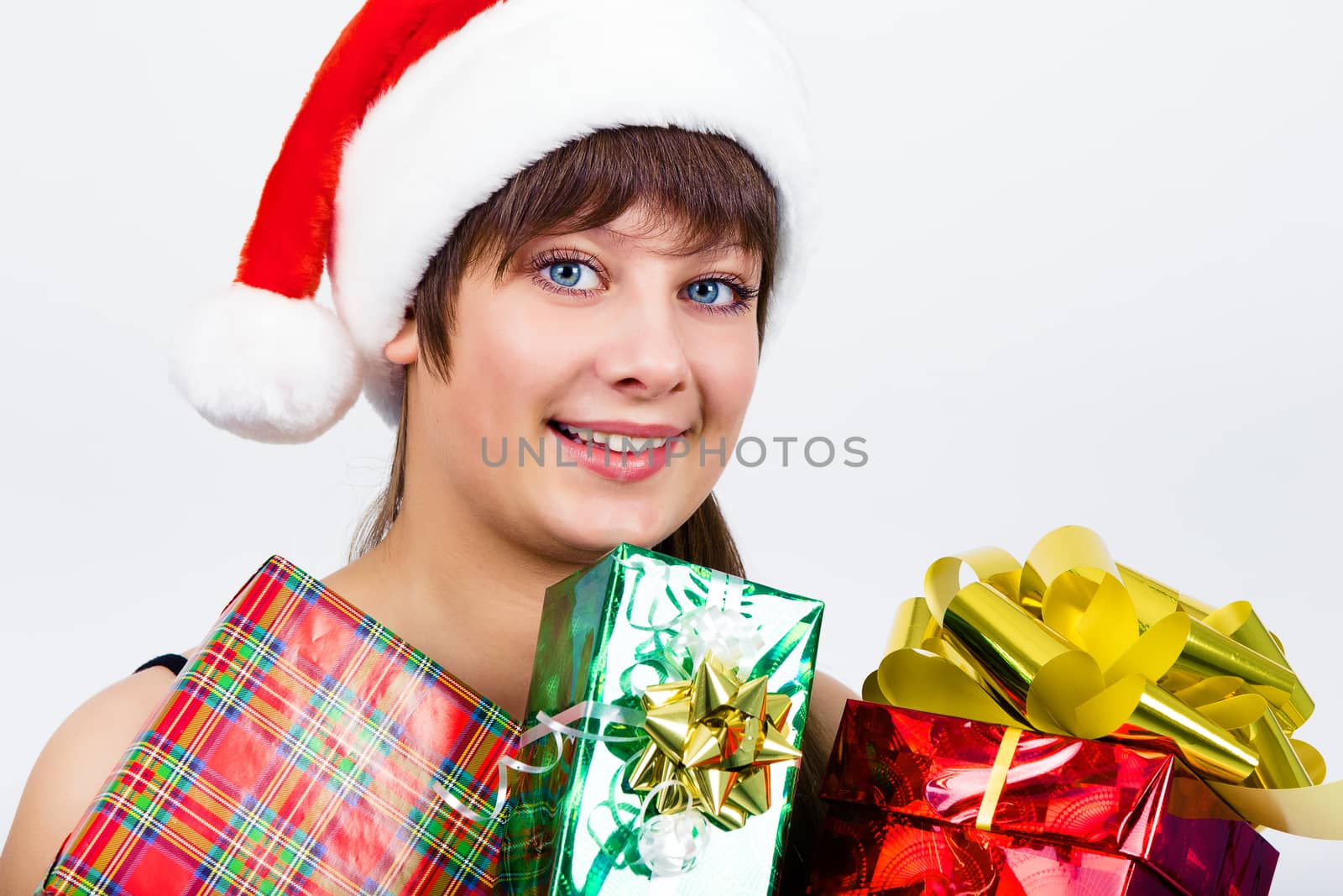 Young blue-eyed beautiful girl in santa hat with presents