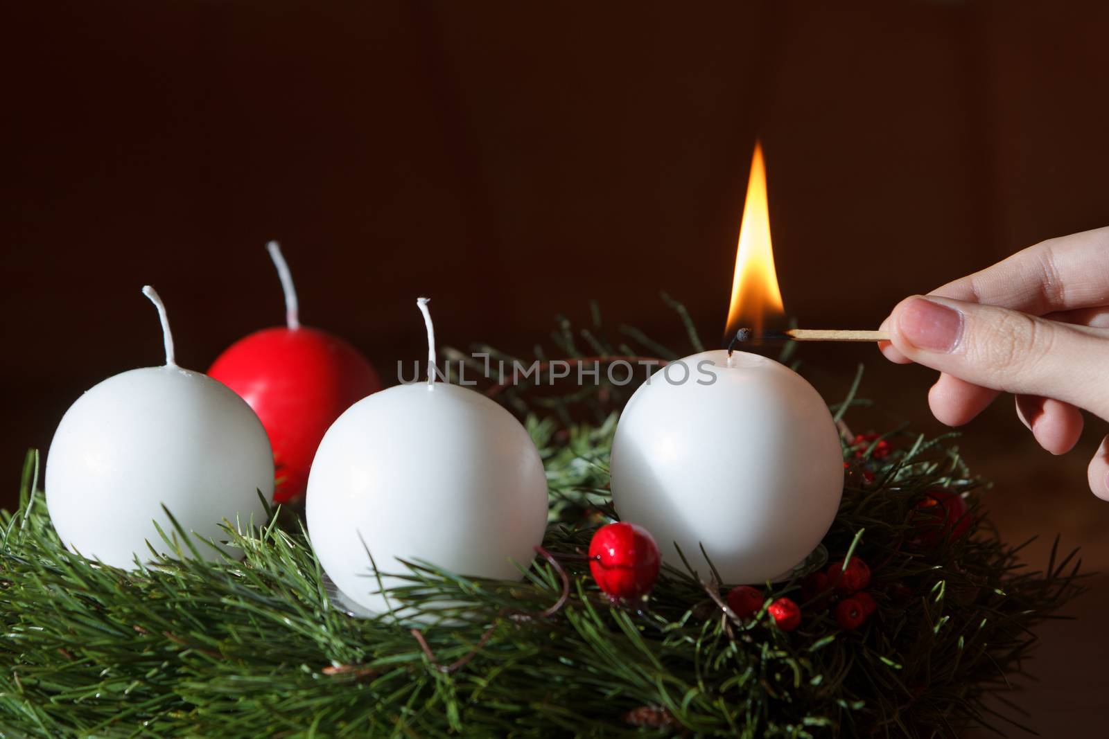 woman's hand lit the first candle of the Advent wreath