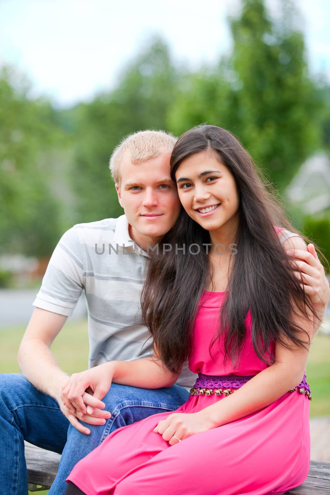 Young,  happy diverse couple sitting together outdoors