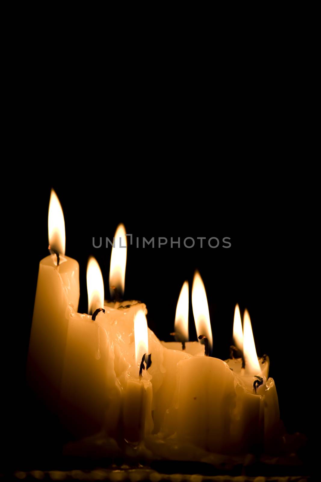 Group of white candles burning in the dark