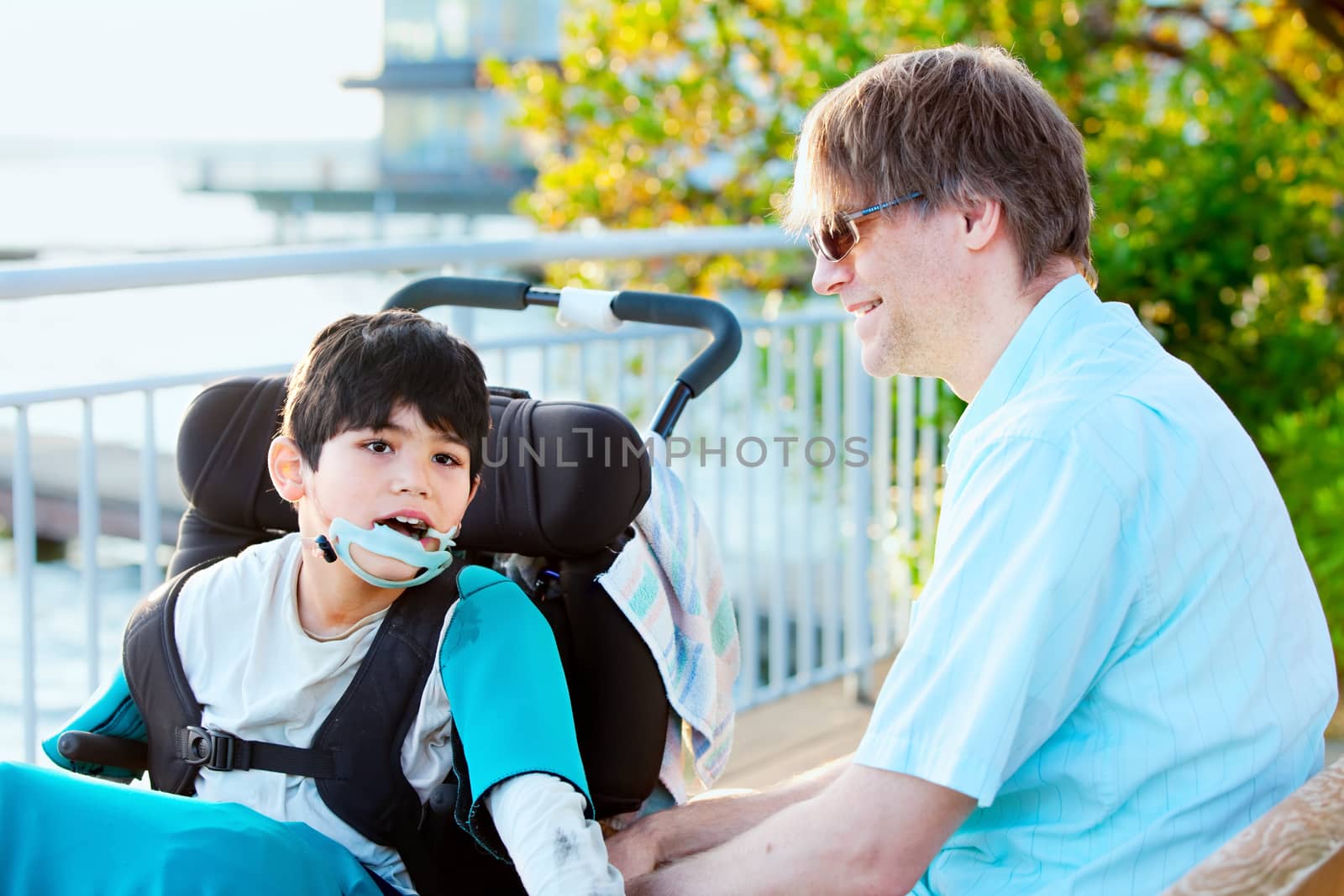 Father talking with his disabled son in wheelchair outdoors