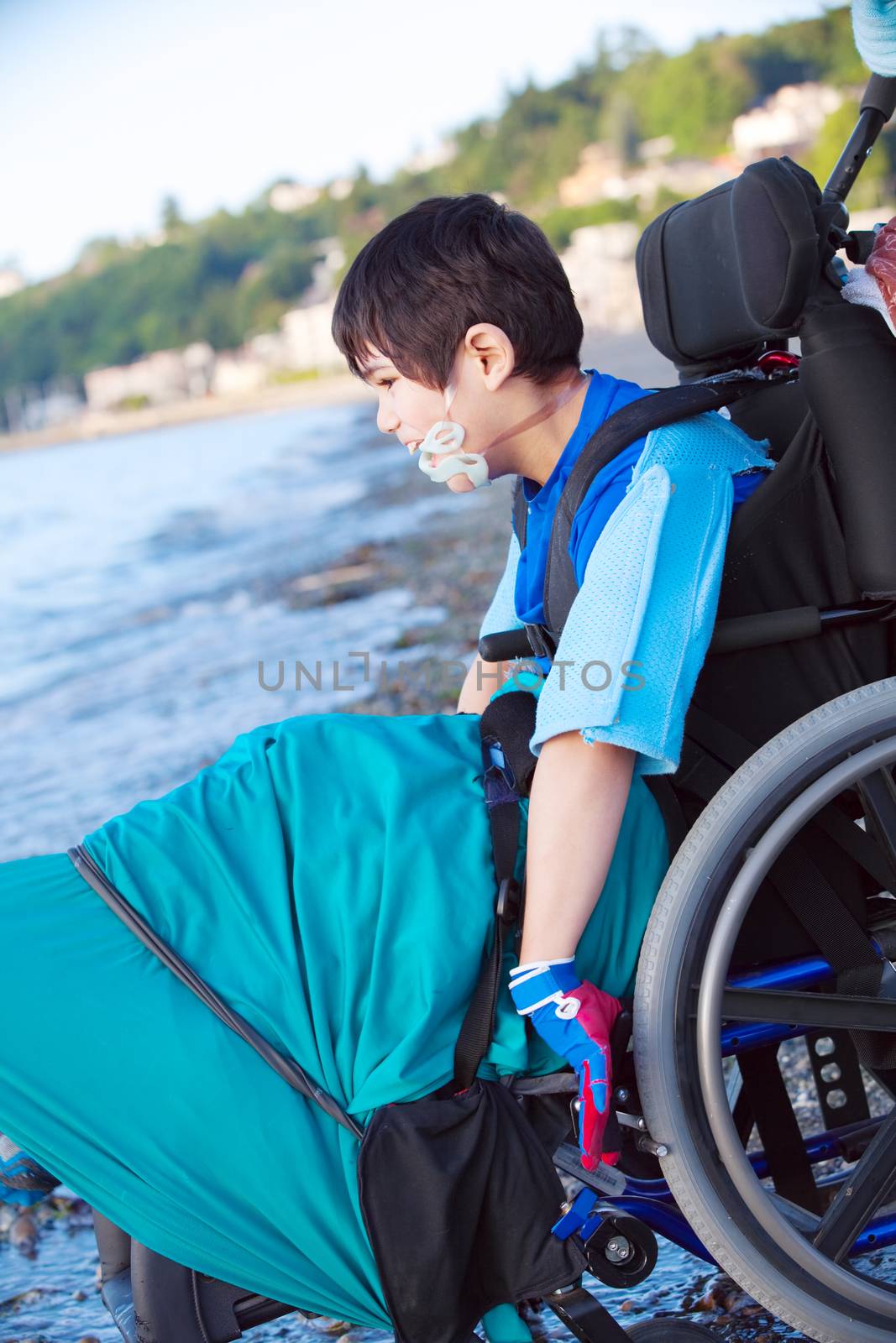 Disabled little boy in wheelchair down by water on beach by jarenwicklund