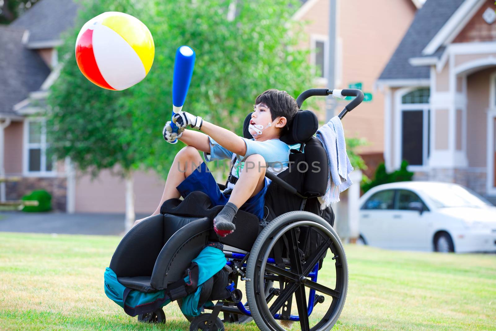 Disabled boy hitting ball with bat at park by jarenwicklund