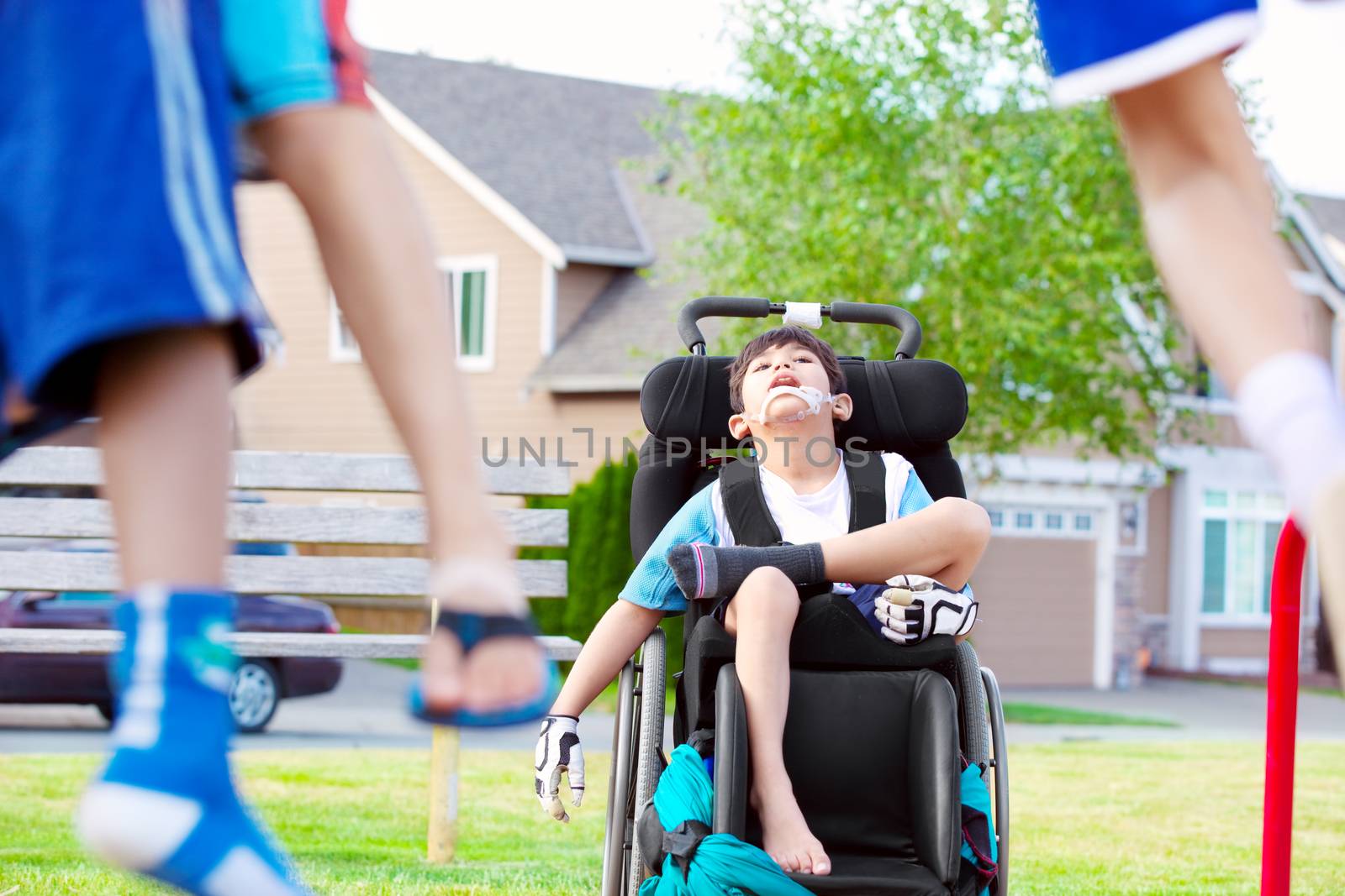 Disabled child in wheelchair watching children play at park by jarenwicklund