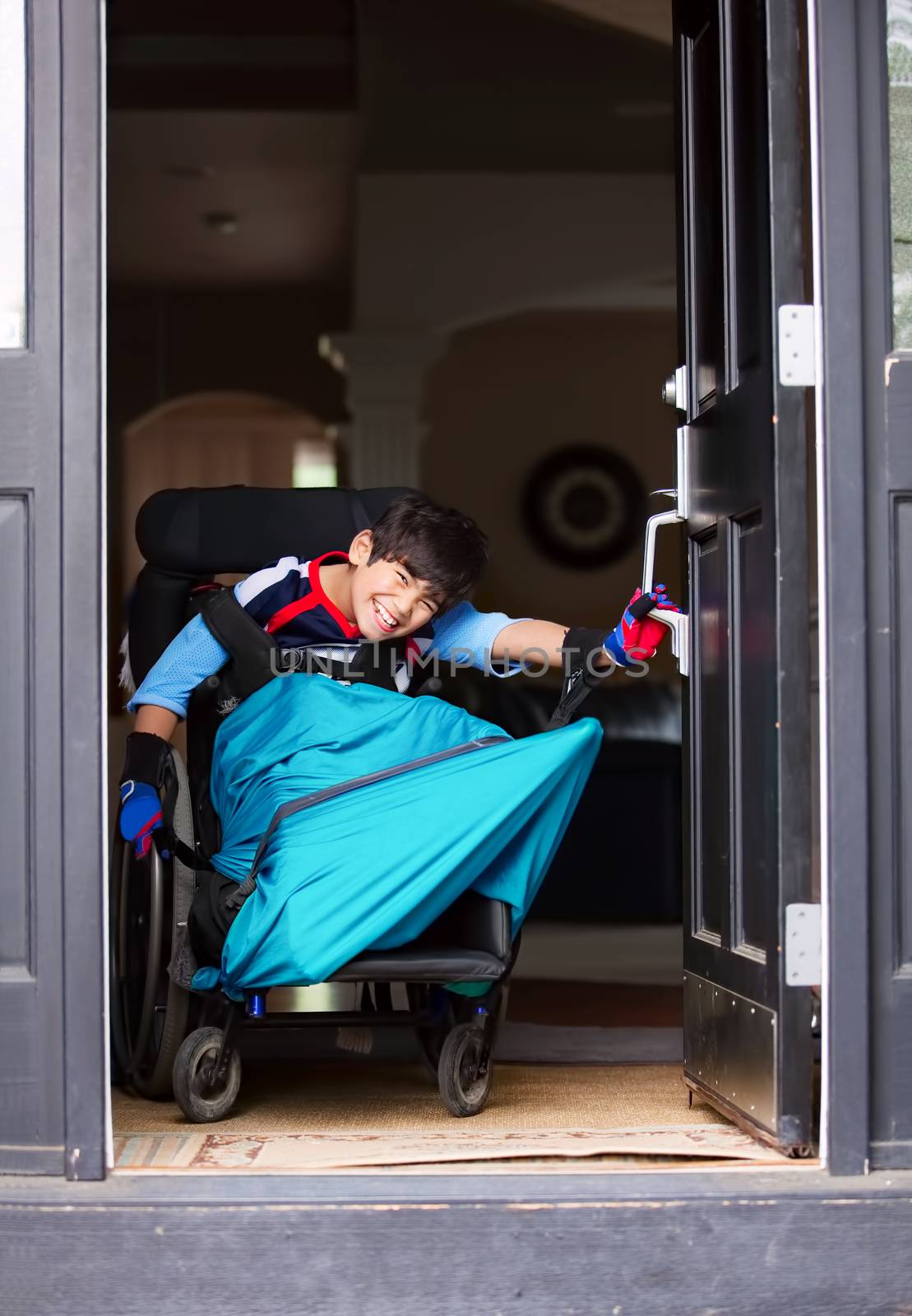 Disabled boy in wheelchair opening front door by jarenwicklund
