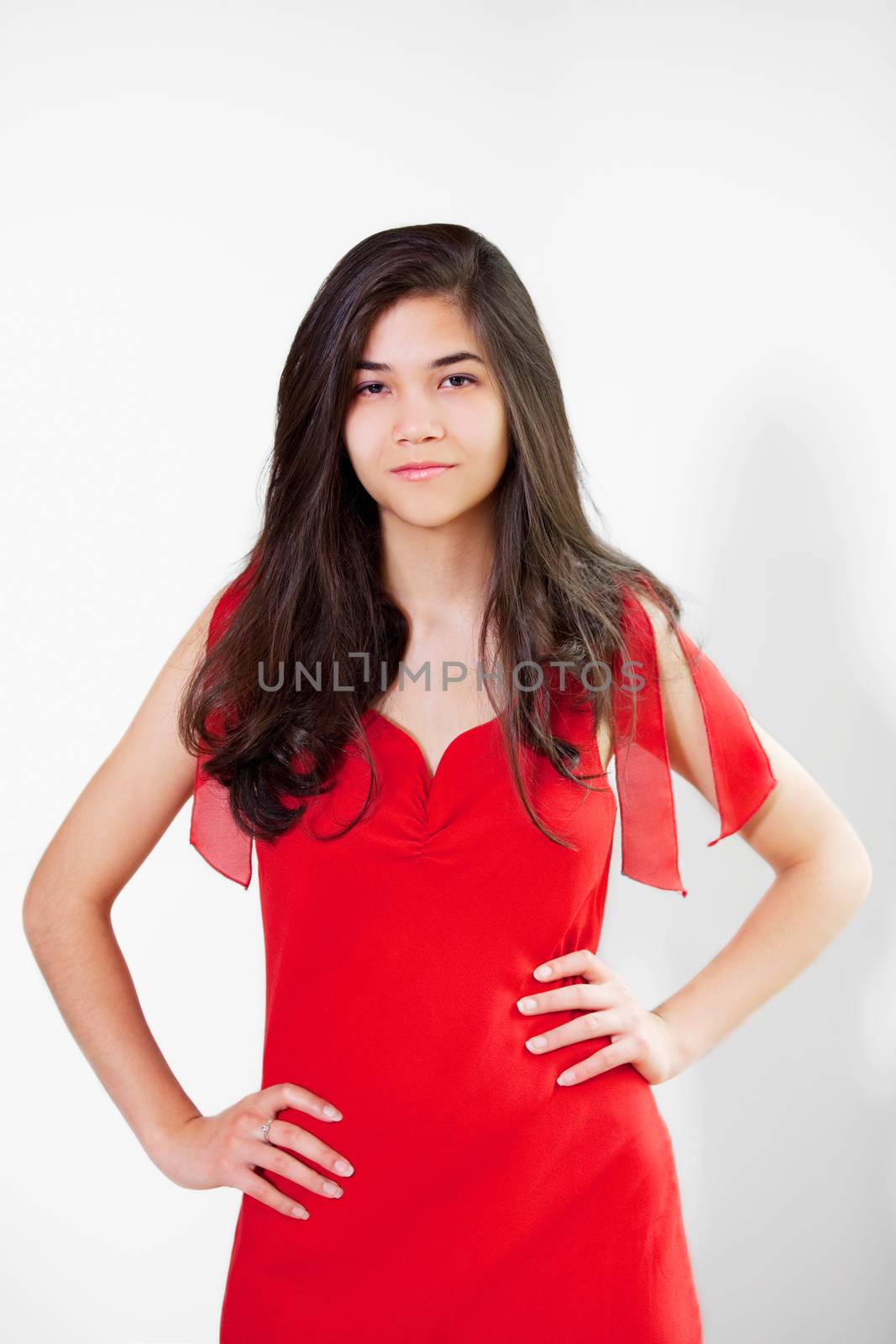 Beautiful biracial teen girl in elegant red dress, hands on hips, relaxed