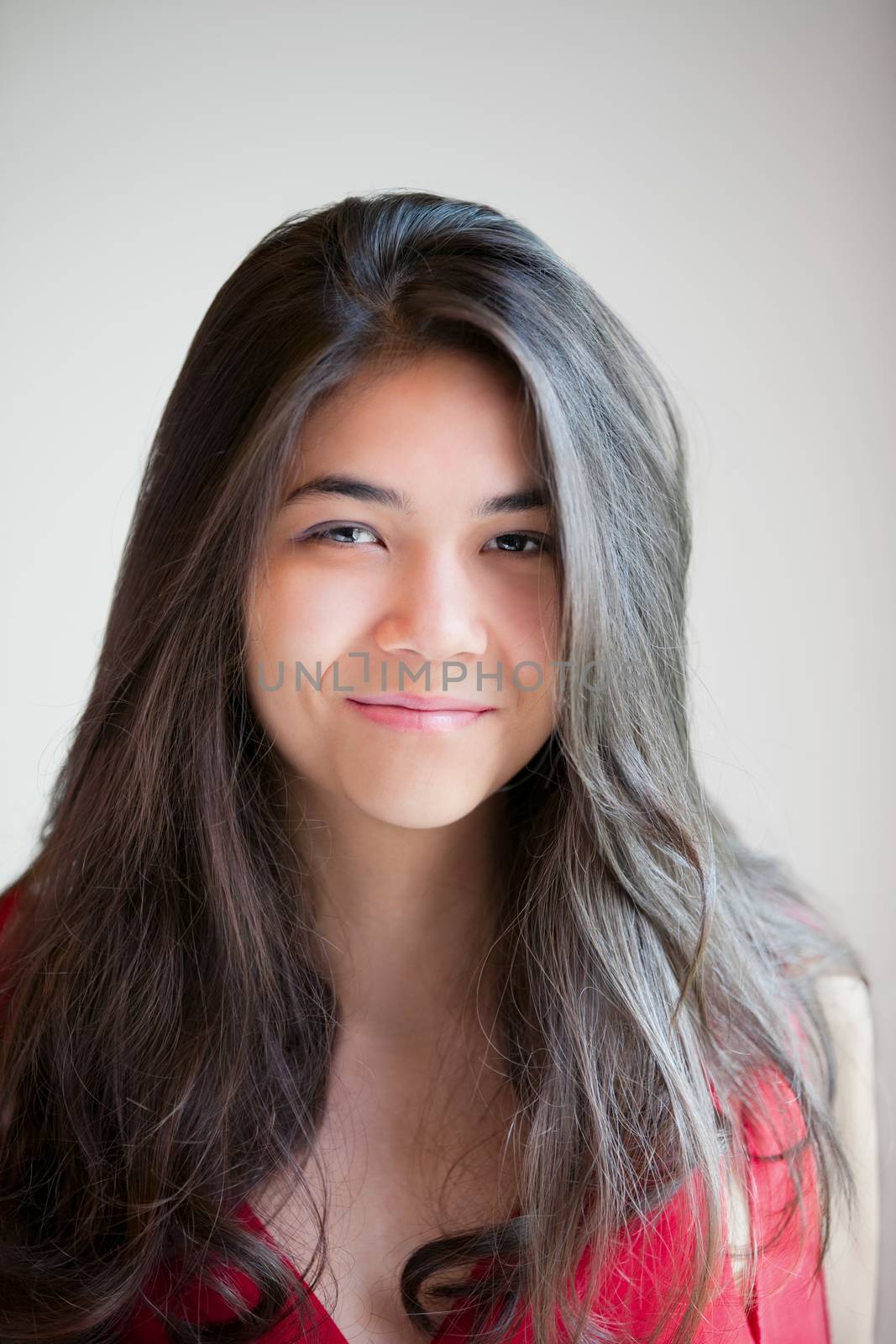 Beautiful biracial teen girl in red dress smiling into  camera