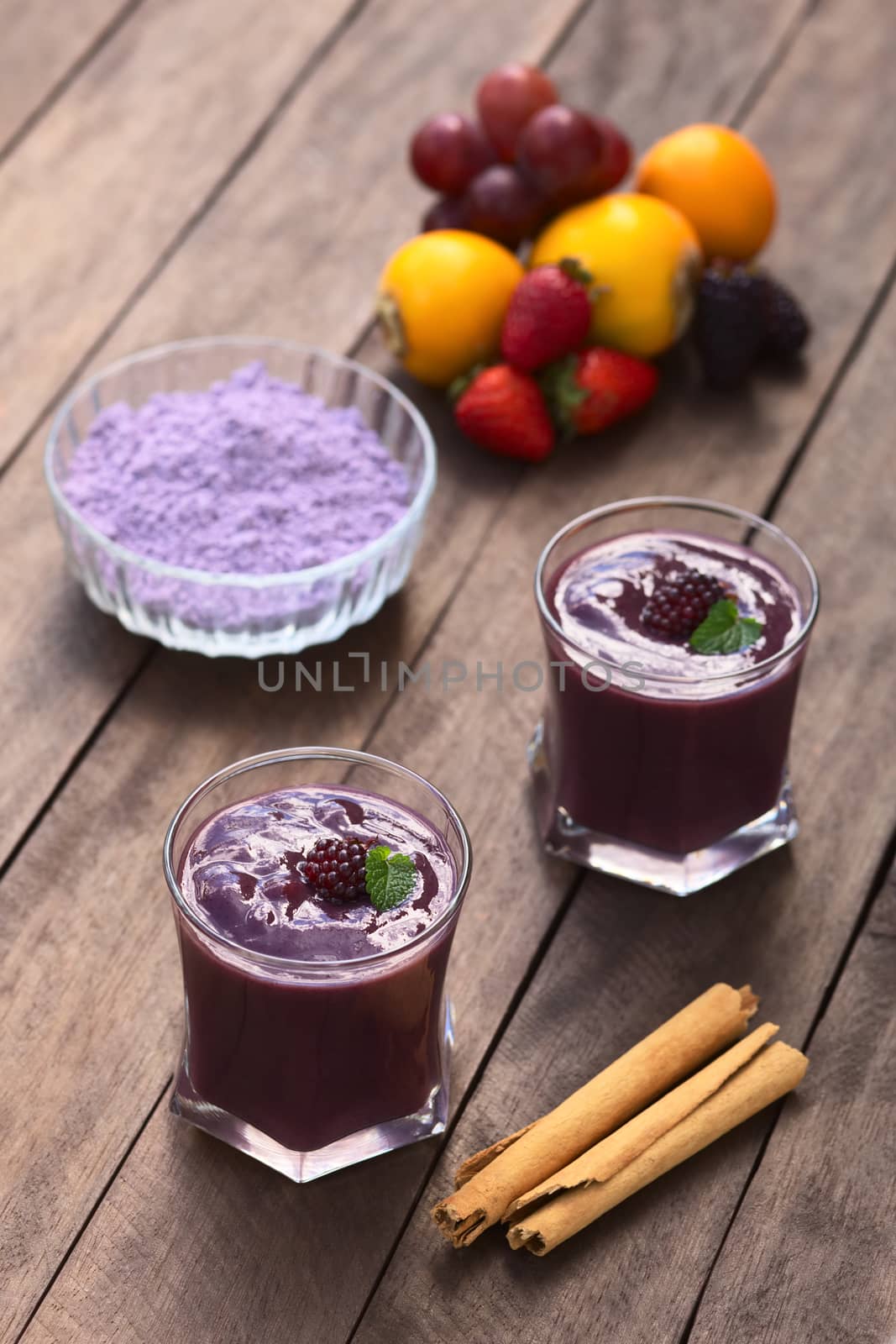 Ecuadorian traditional thick drink called Colada Morada, prepared by cooking purple corn flour and different fruits (for example strawberry, pineapple, naranjilla, grape, babaco, blackberry, etc) and seasoned with panela (cane sugar), cinnamon, allspice and cloves (Selective Focus, Focus on the blackberry on the first drink)