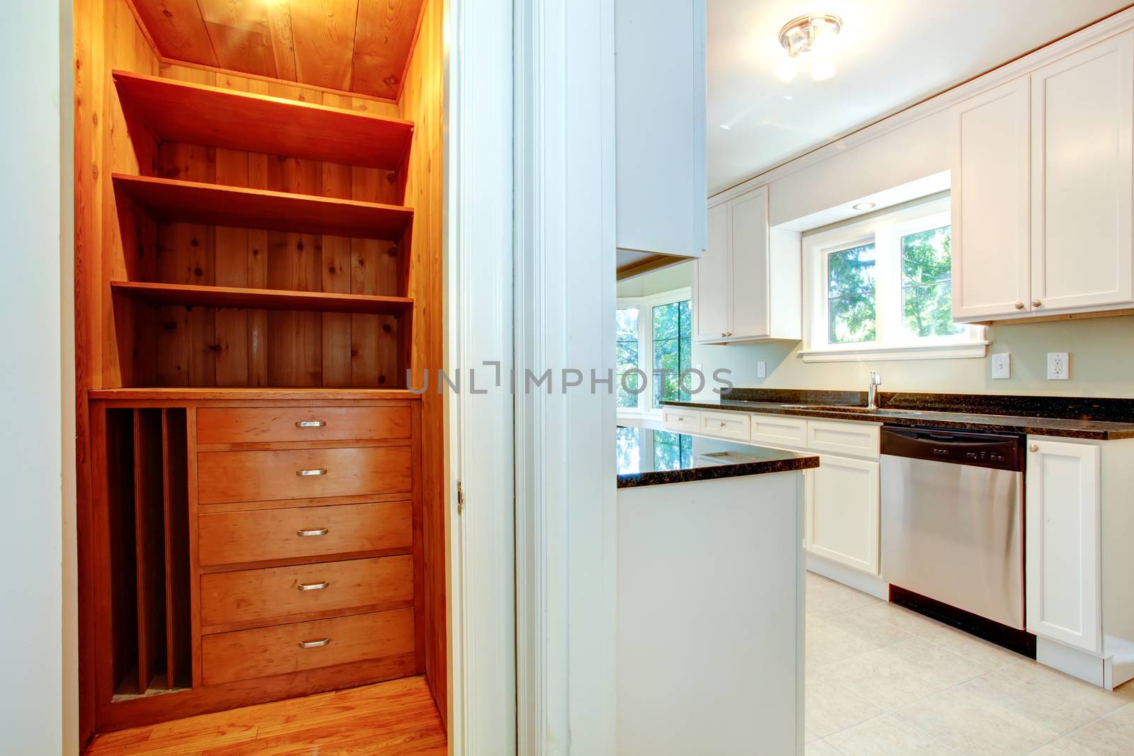 White ktichen room with wooden closet. Small closet with storage shelves and drawers