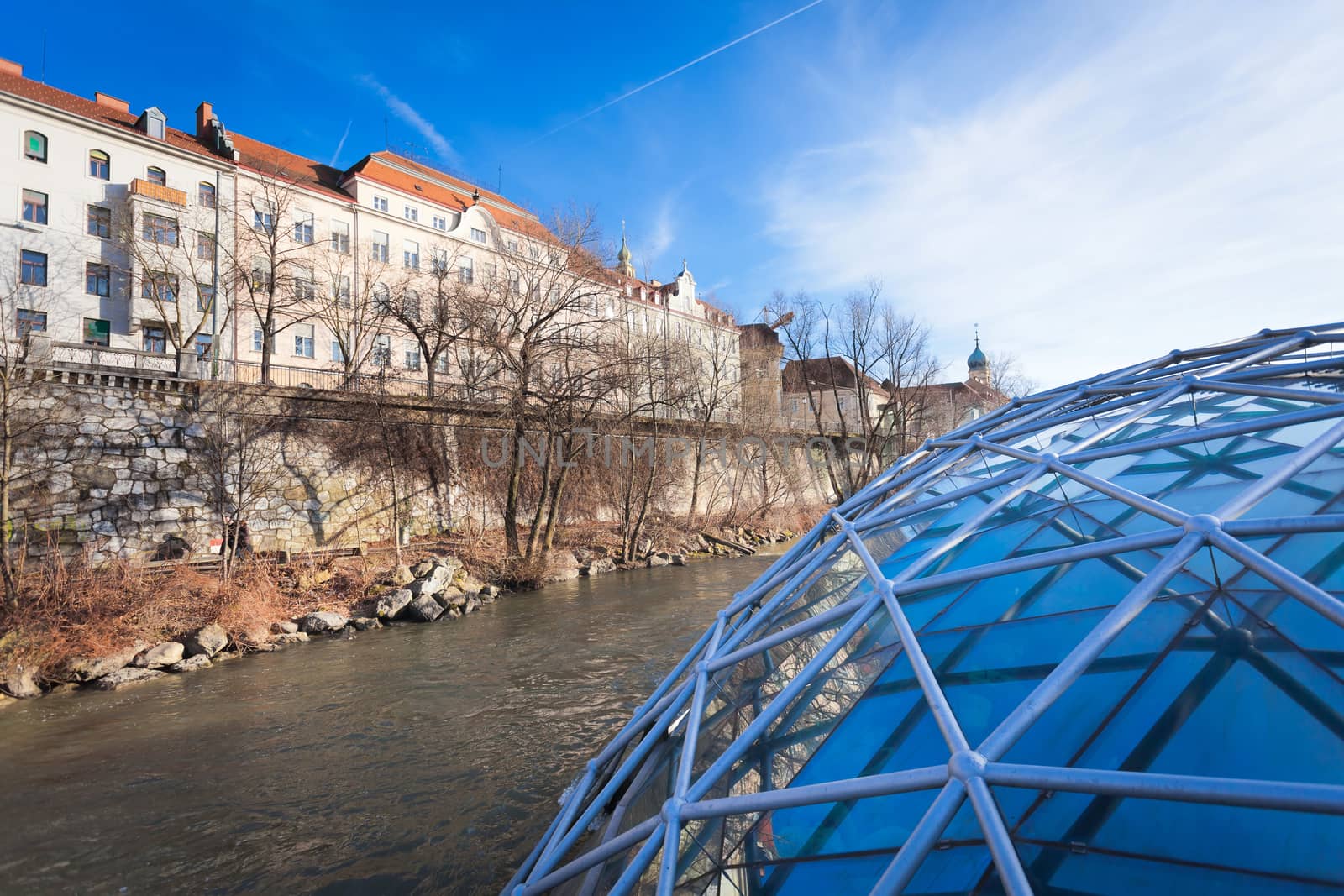 Graz, Austria - January 16, 2011: Graz city seen from Island on Mur river connected by a modern steel and glass bridge, Styria, Graz, Austria