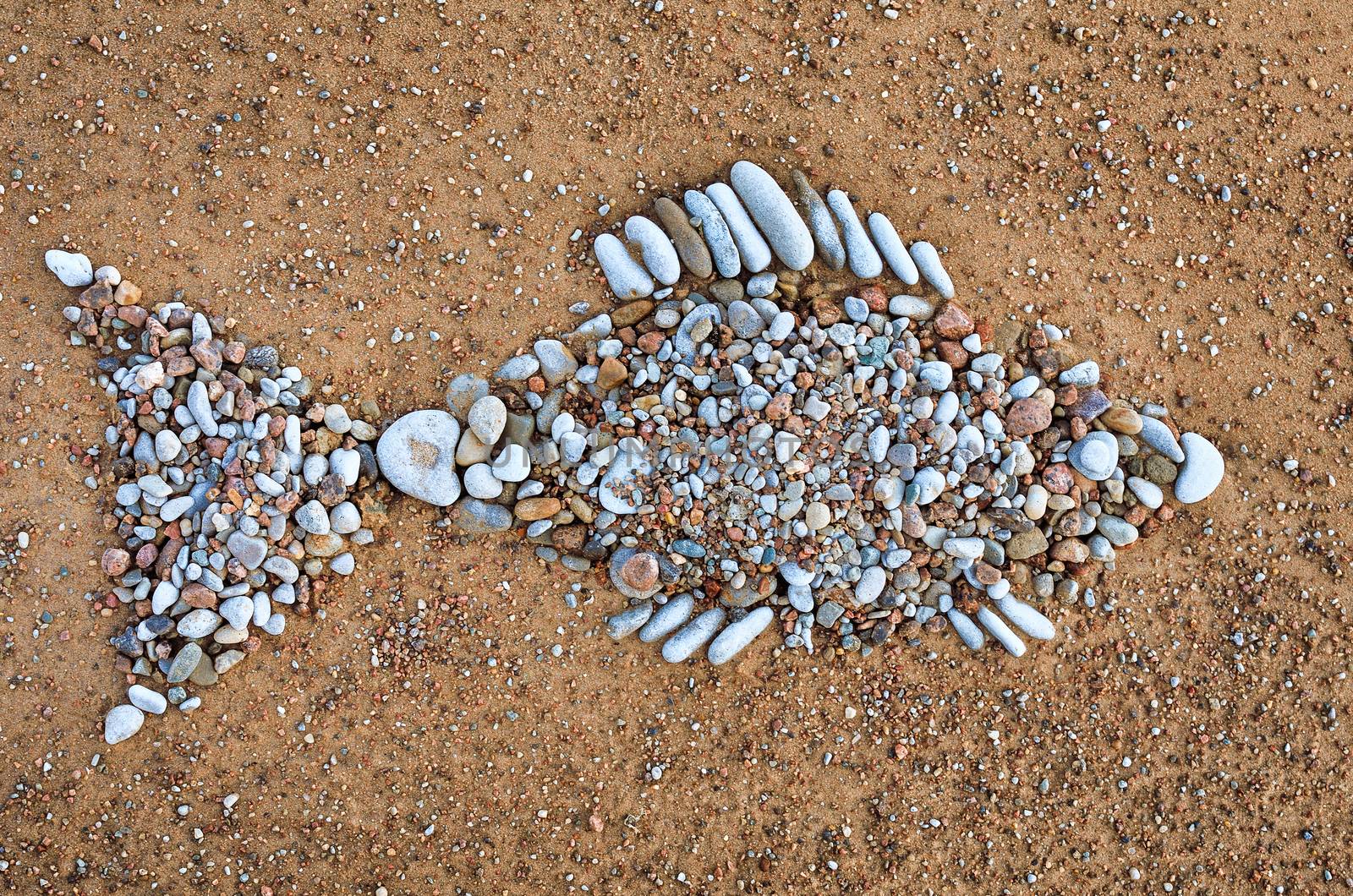 Stone fish symbol of pebbles on the sea boulder