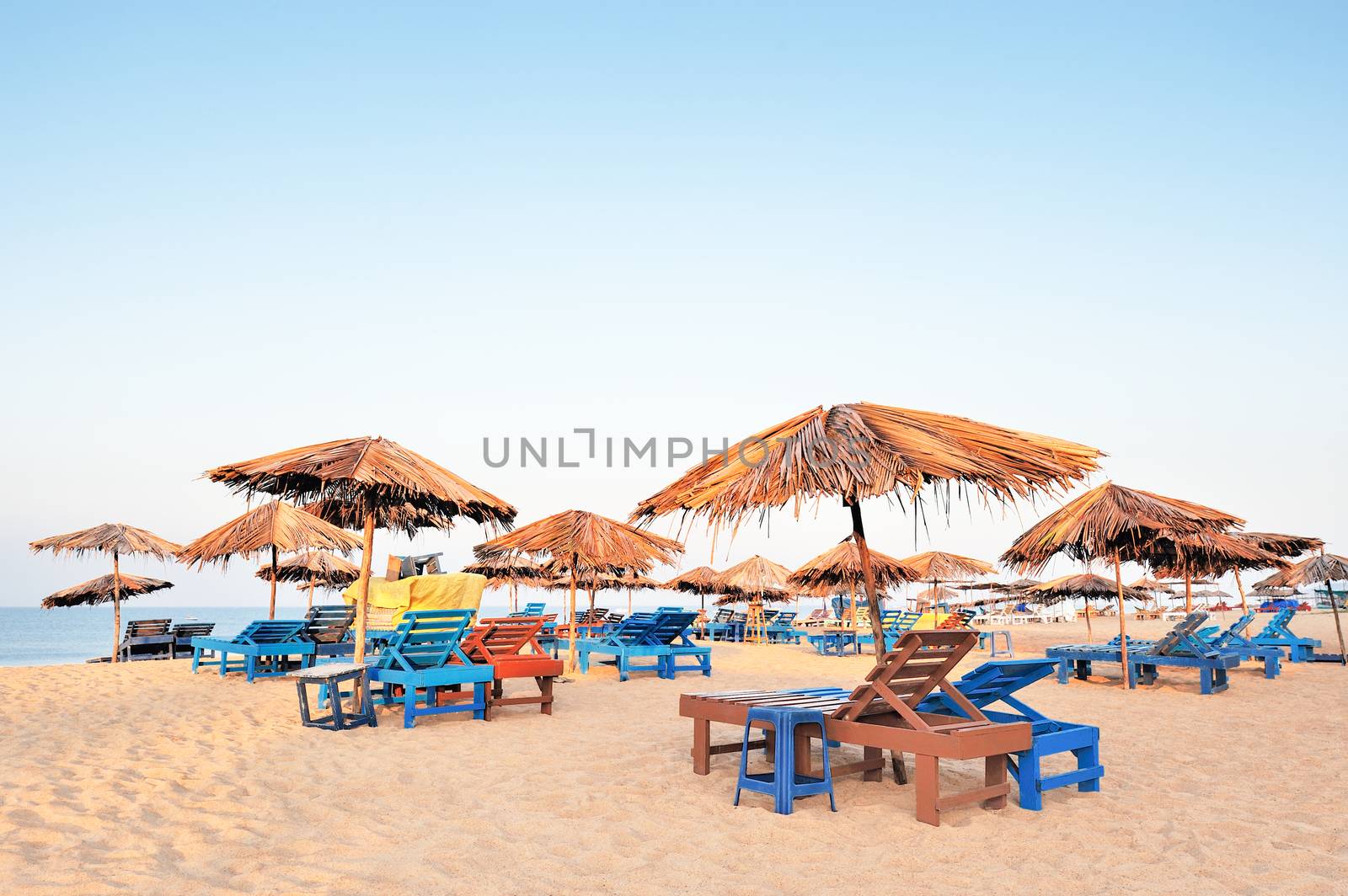 Beach umbrellas and deckchair on the tropical coast in Goa, india