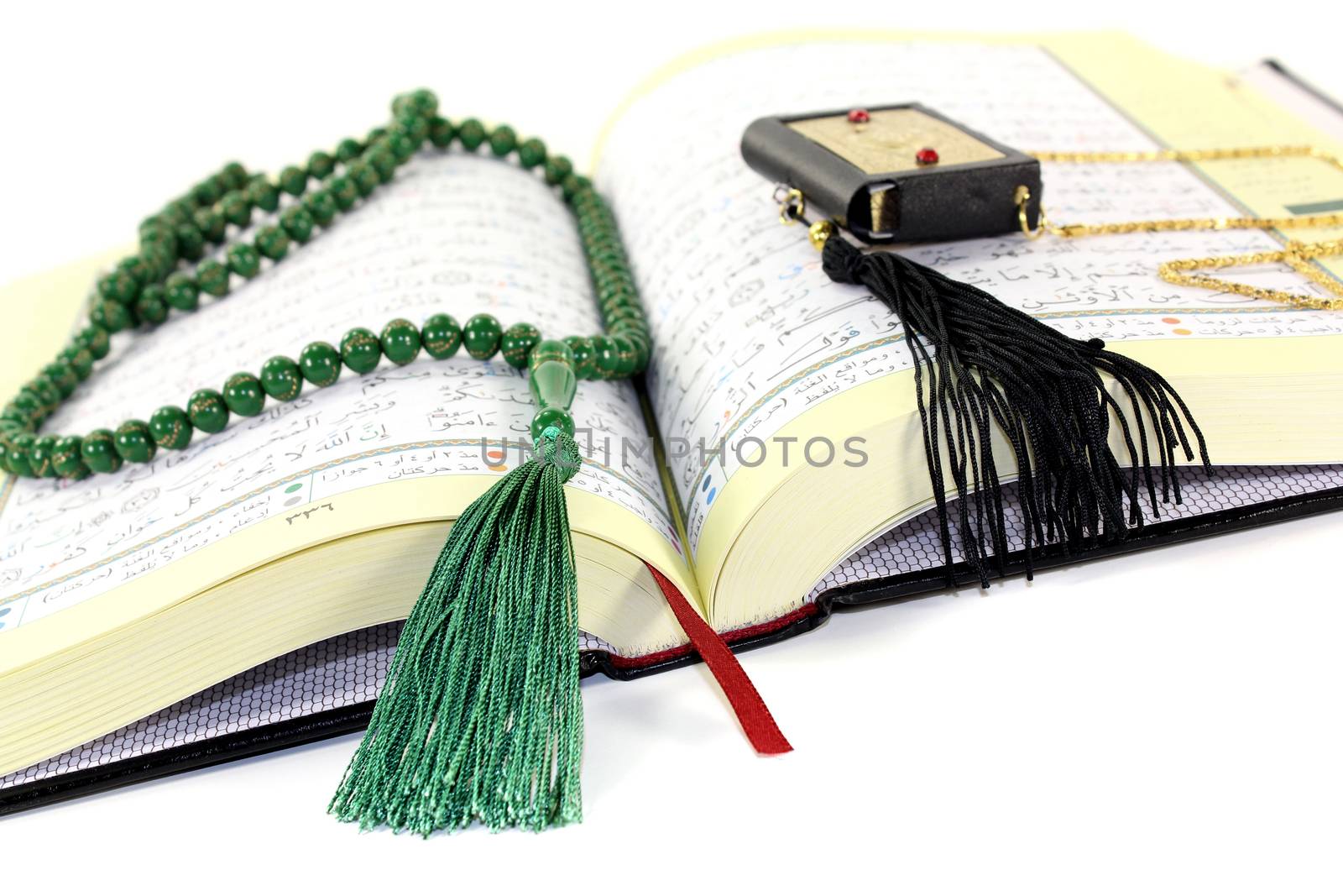 whipped Quran with green rosary before light background