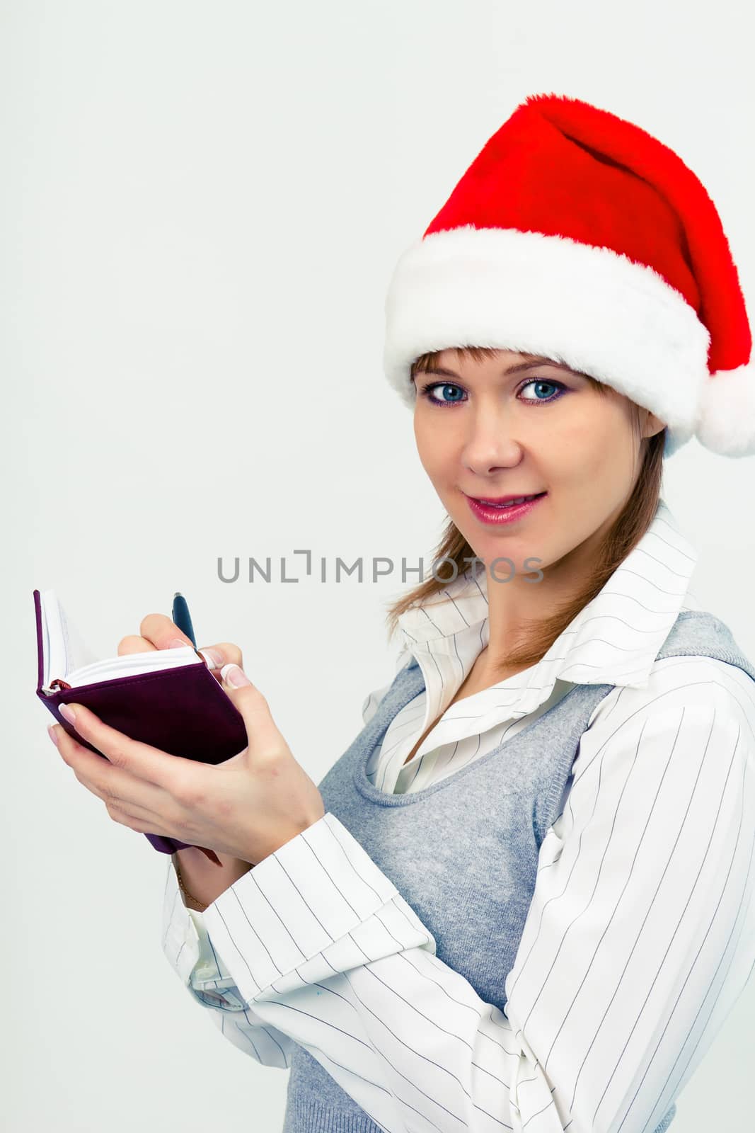 Attractive happy girl in santa hat with a notebook
