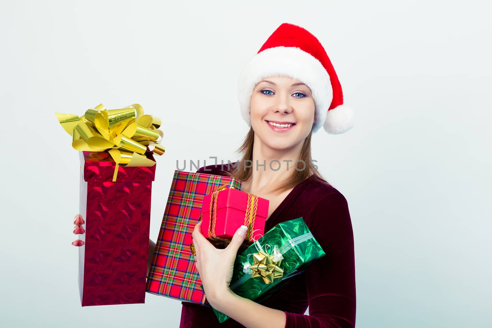Attractive happy girl in santa hat with gift boxes