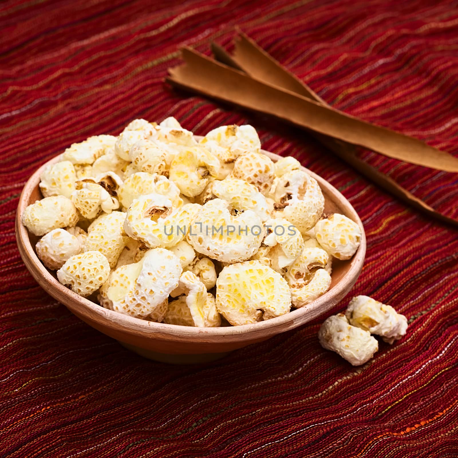 Sweetened popped white corn called Pasancalla eaten as snack in Bolivia served in a clay bowl, photographed with natural light (Selective Focus, Focus on the first part of the snack) 
   